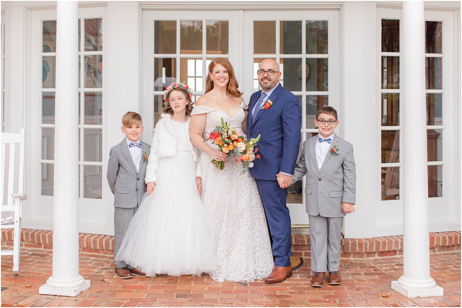 bride and groom pose with three children outside Eagle Manor