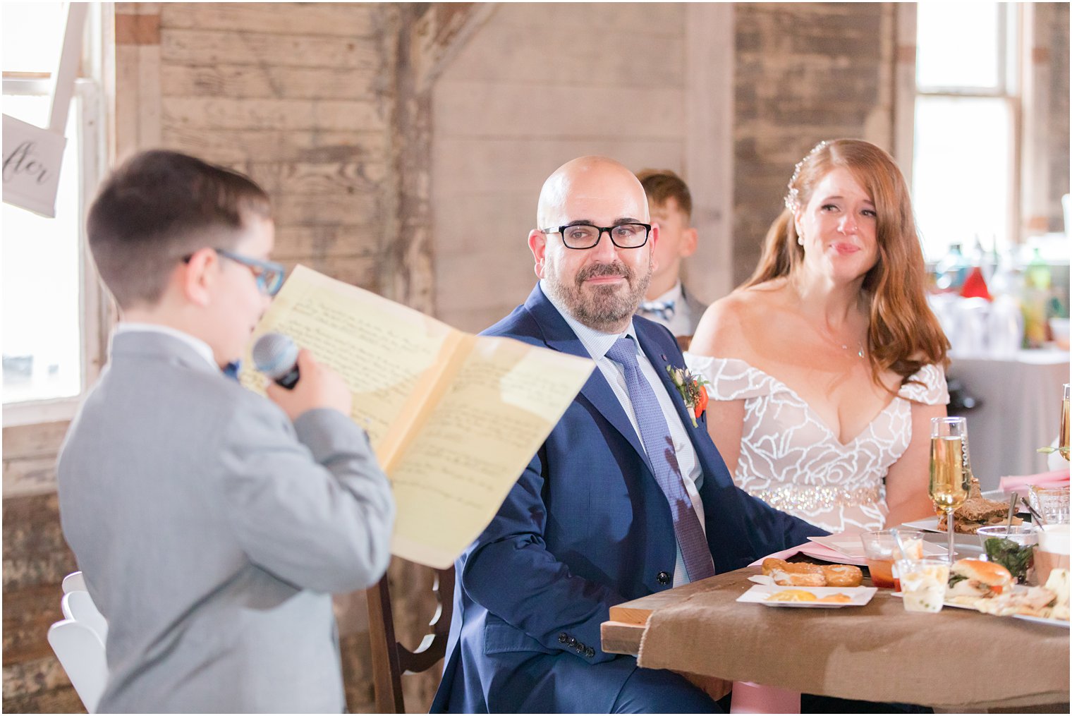 bride and groom listen to son reading speech during NJ wedding reception