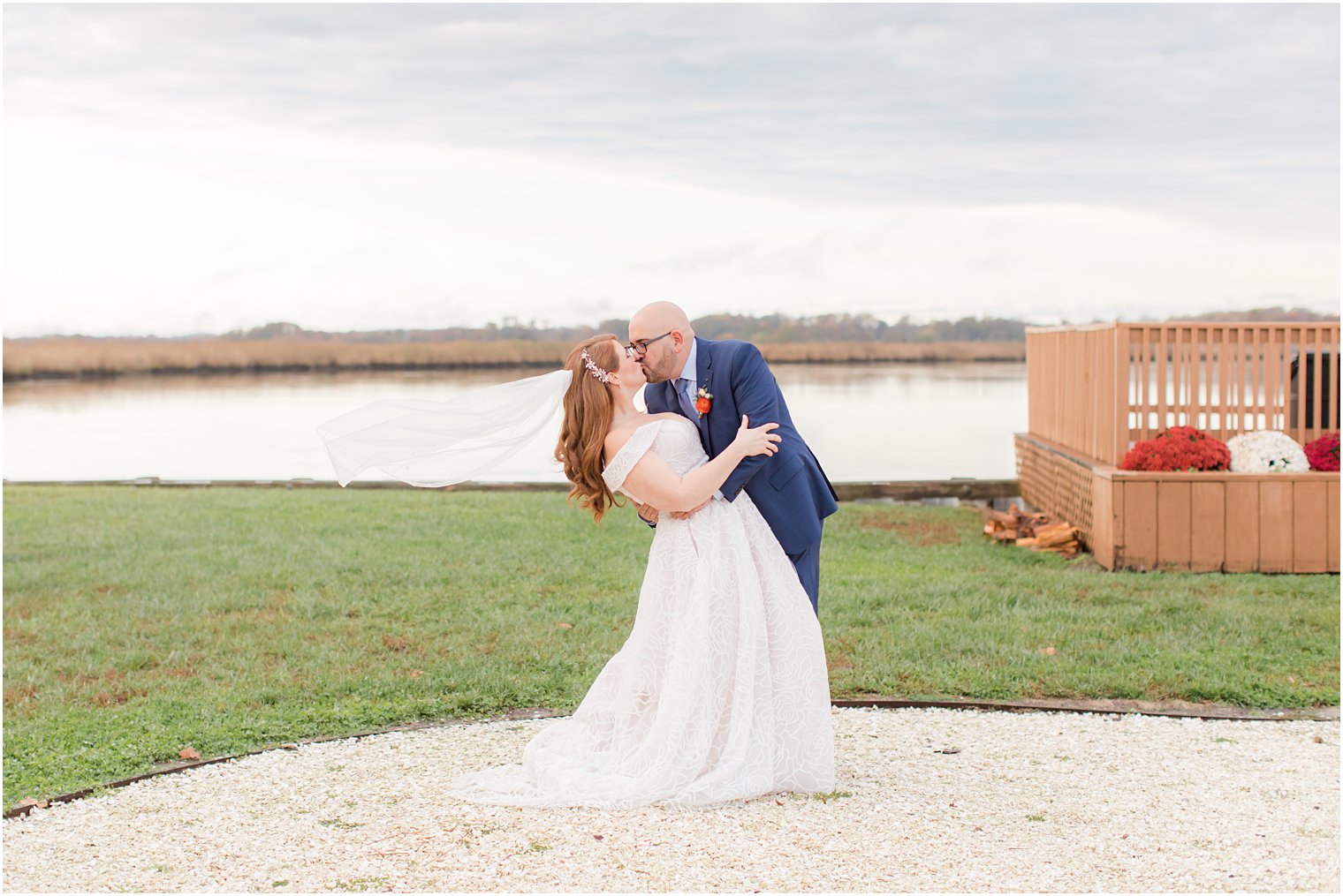 groom kisses bride along water with veil floating