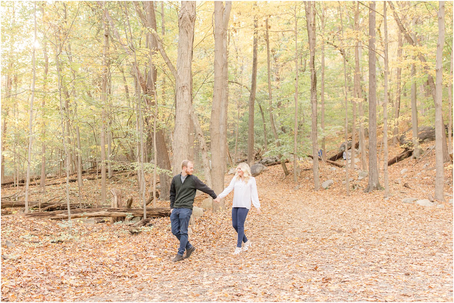 couple holds hands walking through Ramapo Reservation