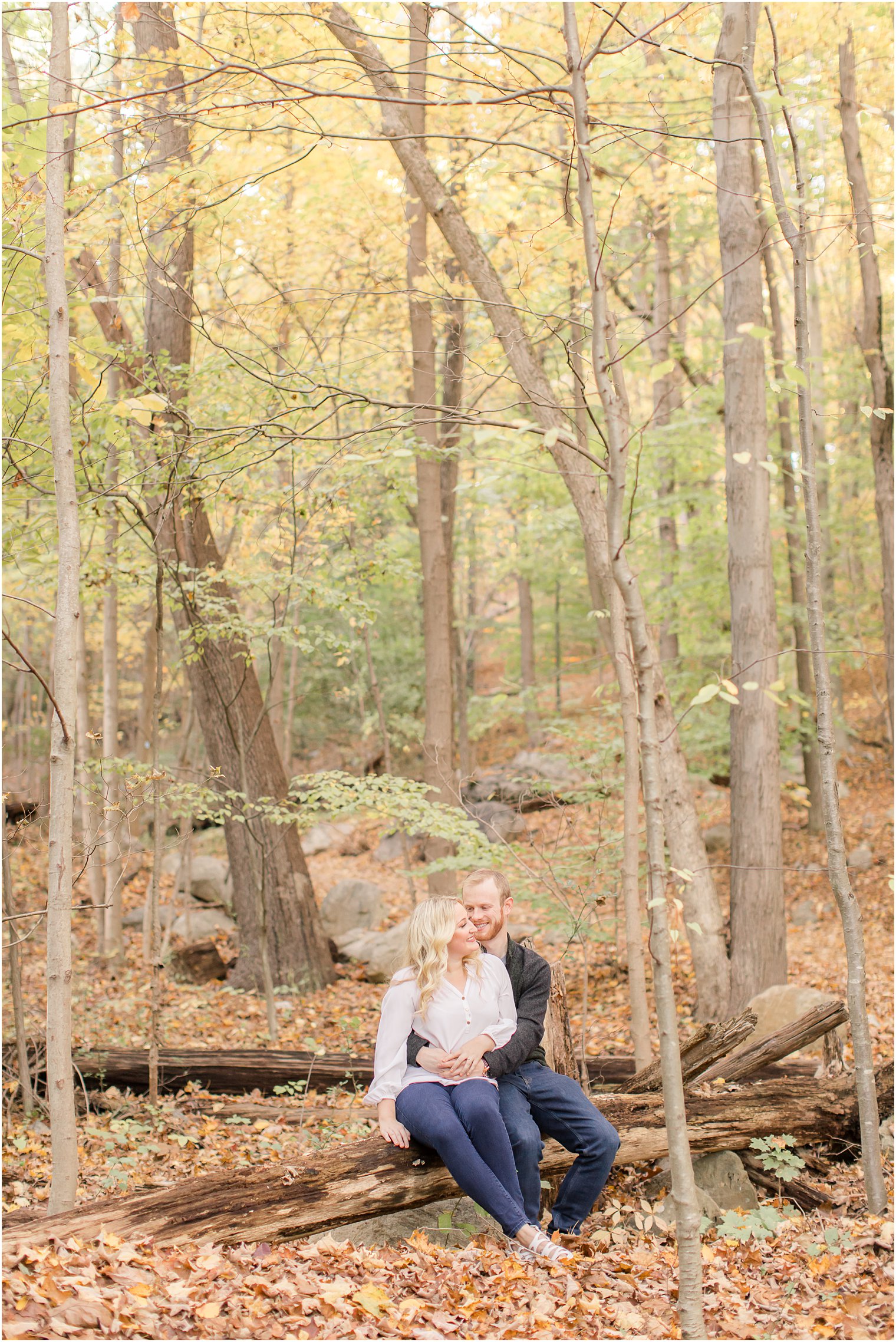 bride and groom sit on wood pile at Ramapo Reservation