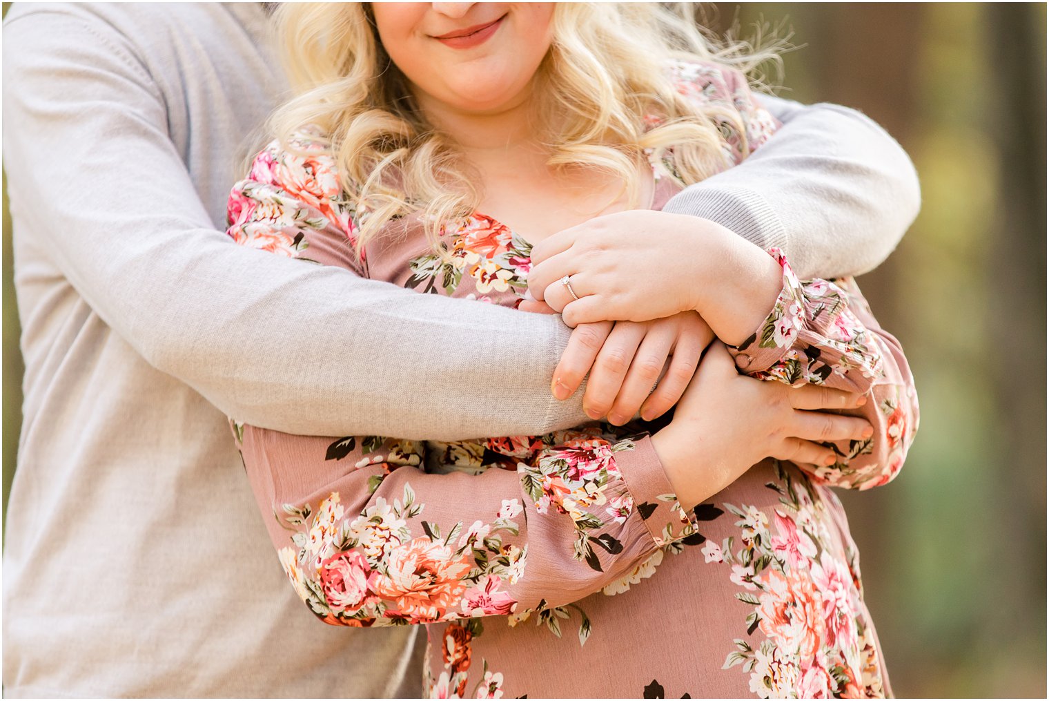 bride holds groom's hands around her chest showing off engagement ring