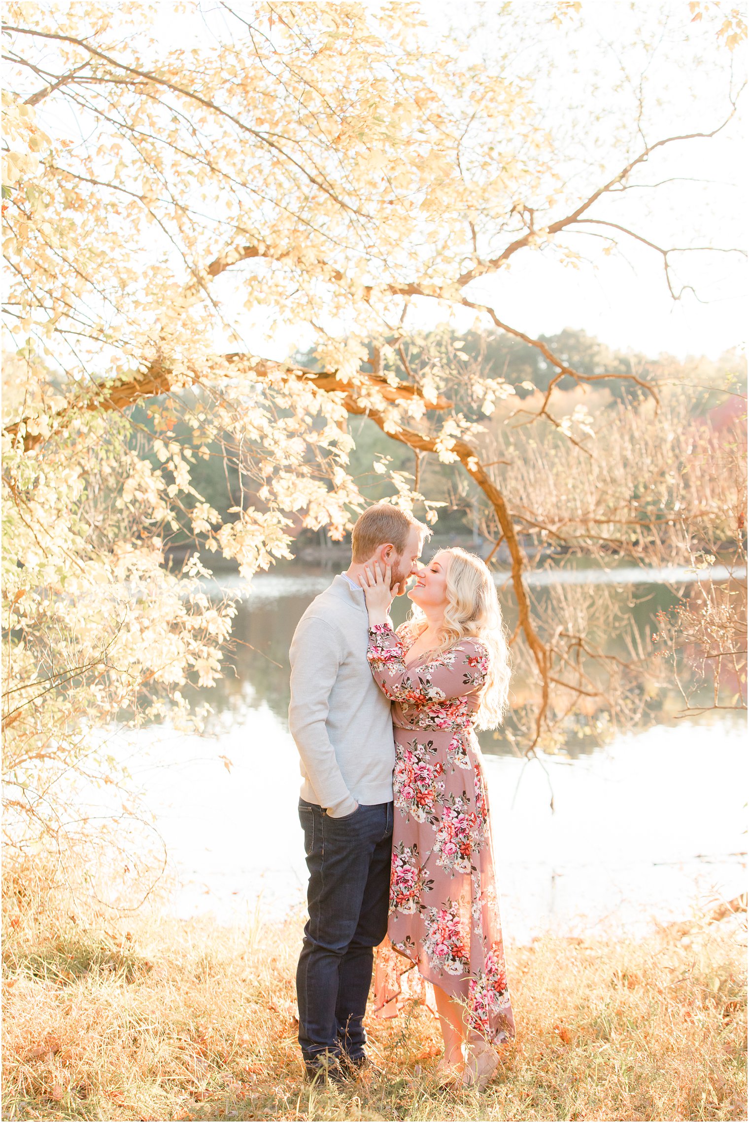 engaged couple kisses by tree with yellow leaves at Ramapo Reservation