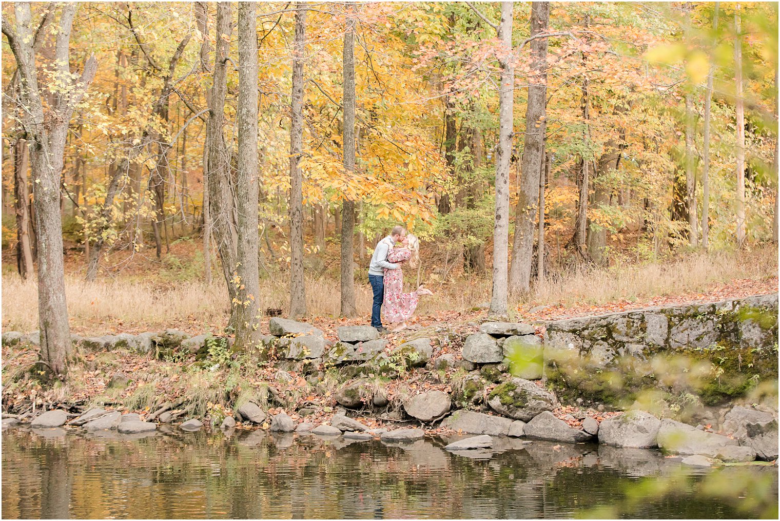 engaged couple kisses alongside river on NJ reservation
