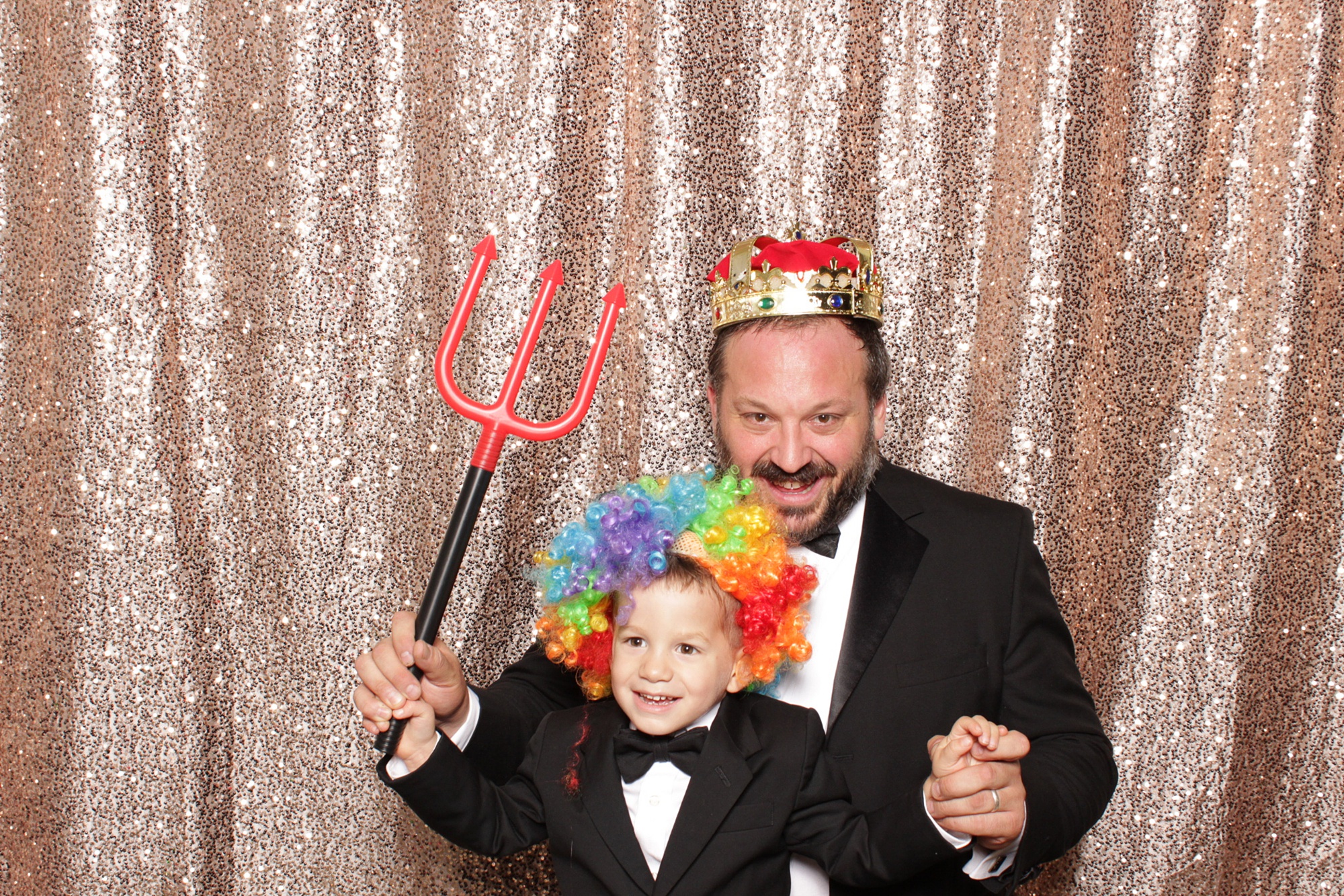 dad and son pose in photo booth with clown wig