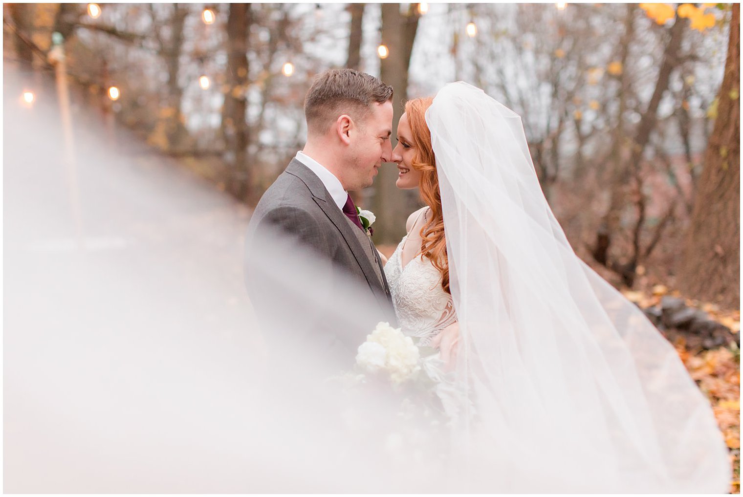 bride and groom pose with veil wrapped around them