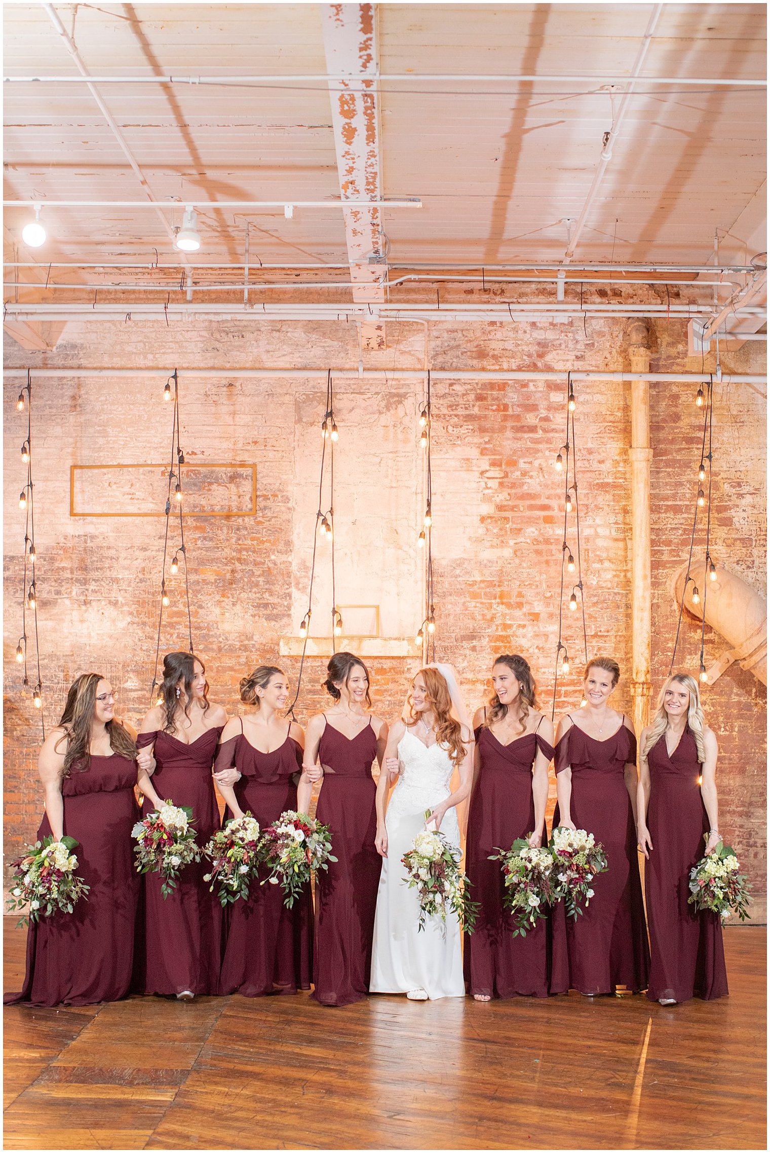 bride walks with bridesmaids in burgundy gowns