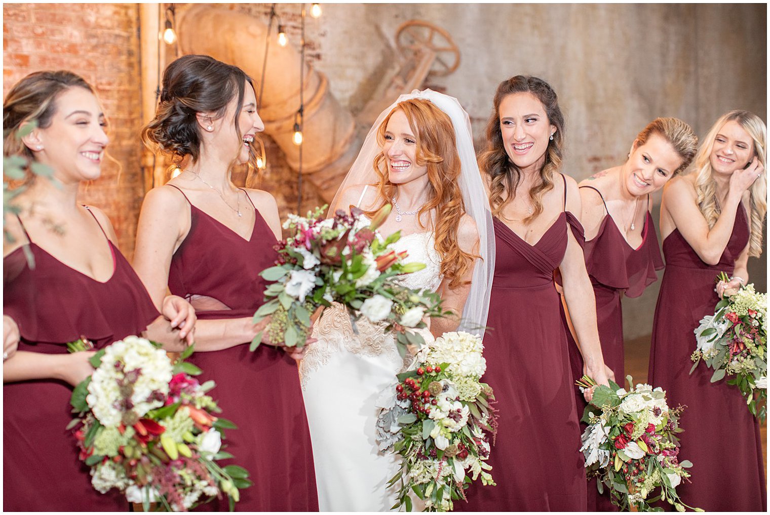 bride laughs with bridesmaids holding bouquet with winter berries 