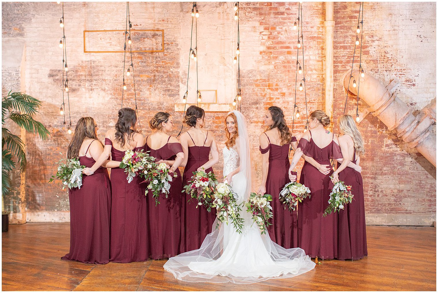 bridesmaids hold bouquets behind back while bride smiles