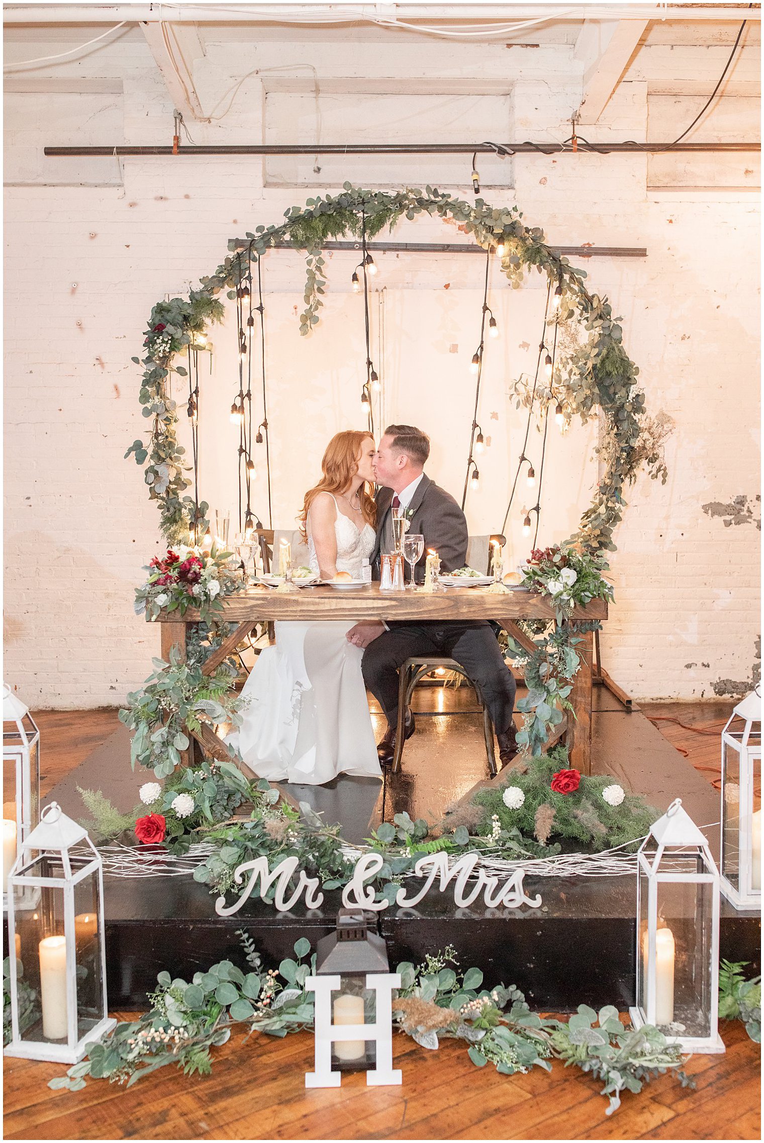 sweetheart table for Art Factory Studios wedding with greenery covered metal arbor and lanterns