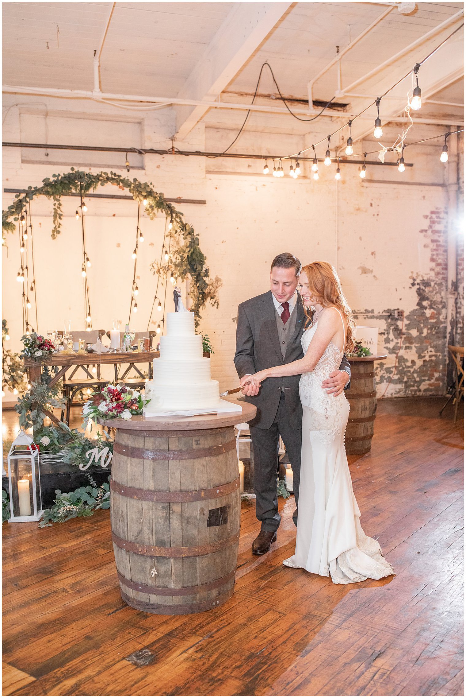 newlyweds cut wedding cake resting on wooden barrel 