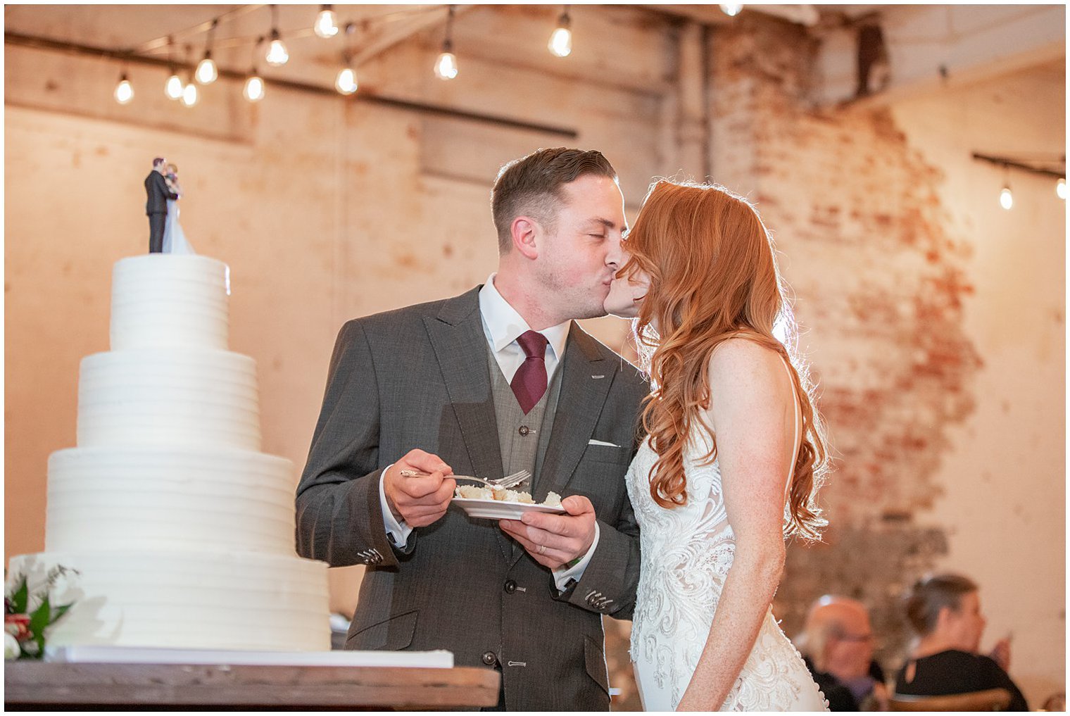 newlyweds kiss while cutting wedding cake during NJ reception