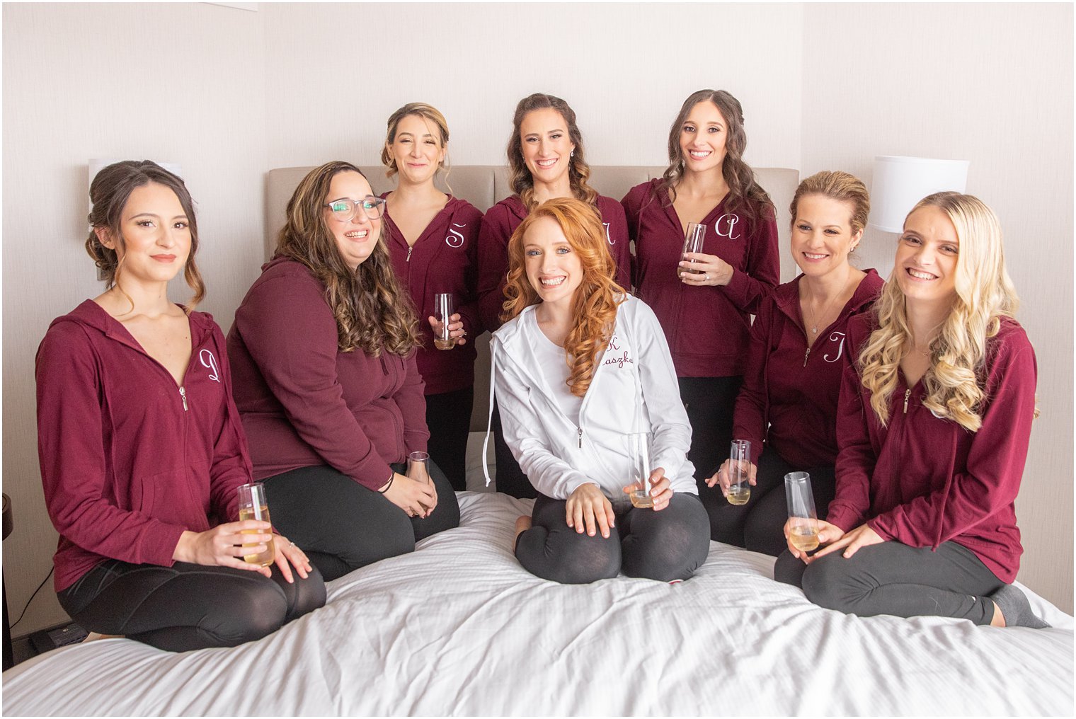 bride poses with bridesmaids in matching burgundy jackets before Art Factory Studios wedding