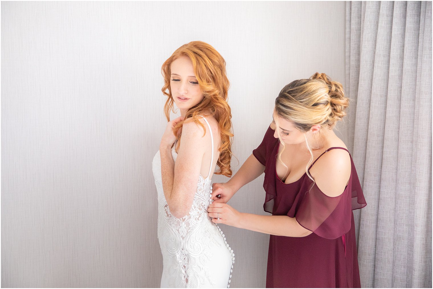 bridesmaids helps bride with buttons on wedding dress