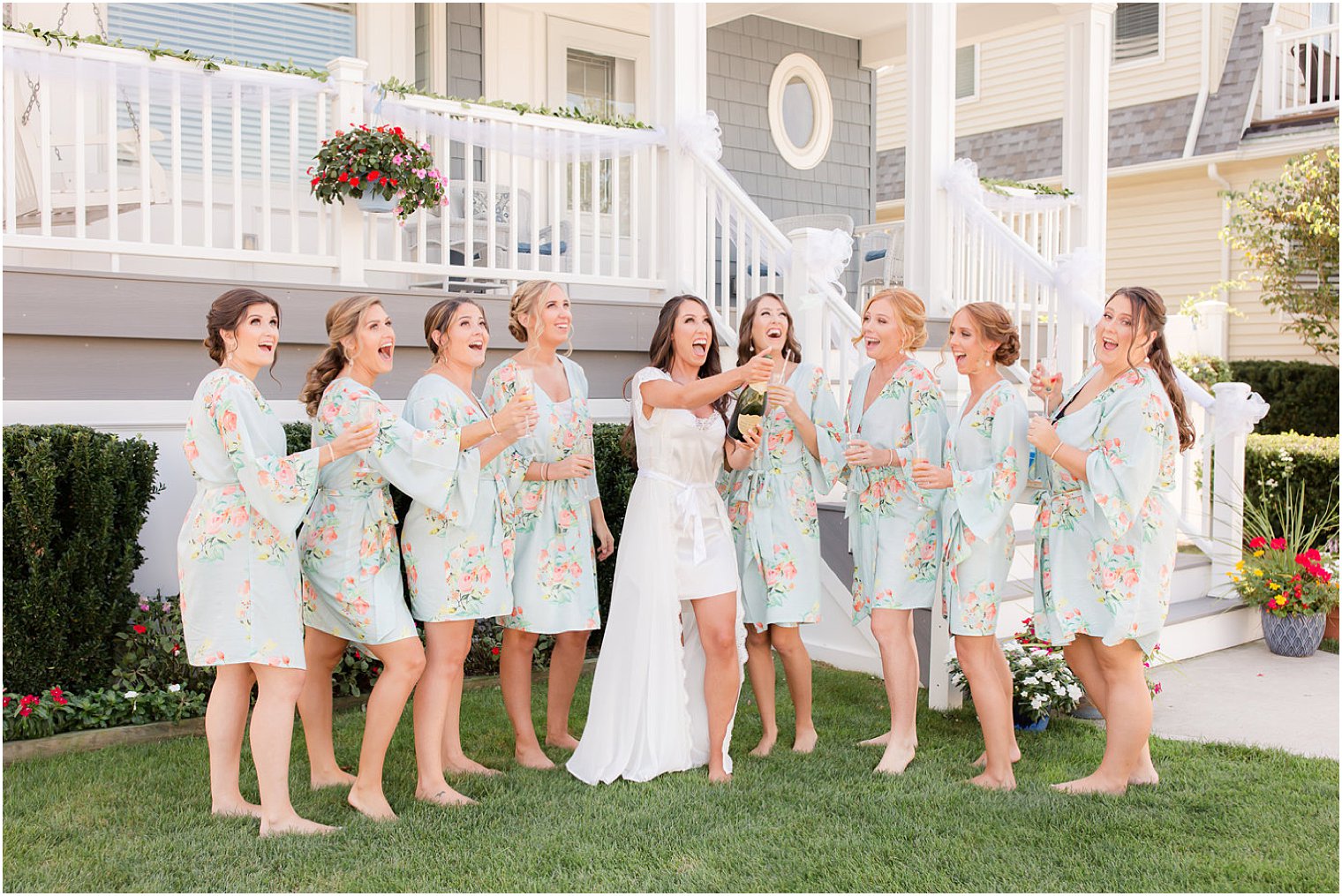 bride popping champagne with bridesmaids outside their house