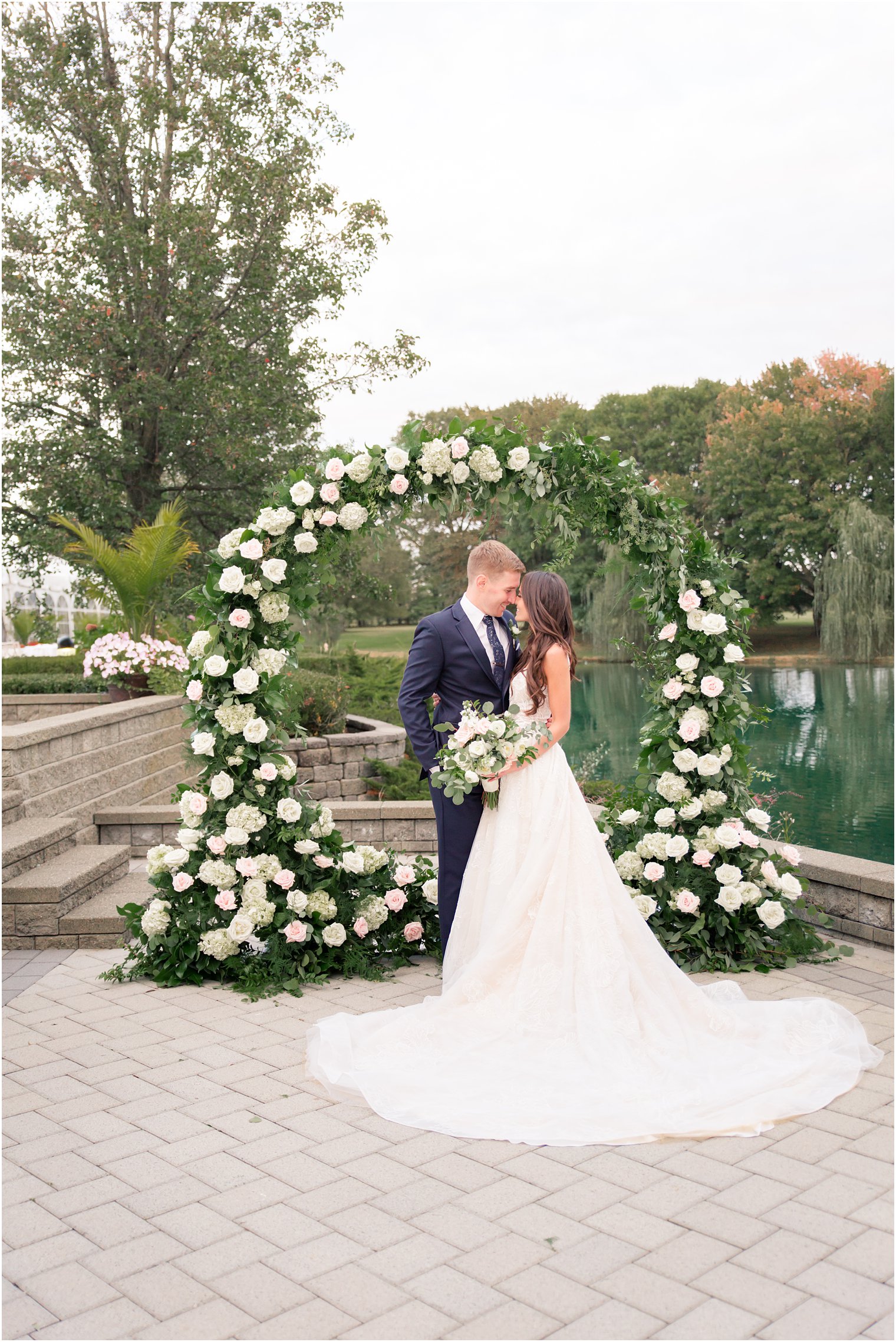 Bride and groom in front of oversized floral wreath by Bespoke Floral Design