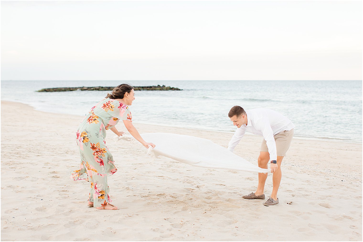 couple spreads out blanket during engagement photos in New Jersey