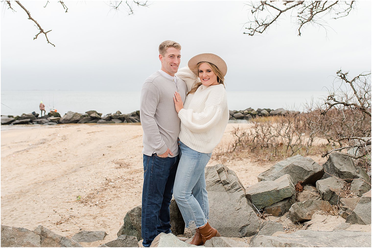 engaged couple poses on rocks of New Jersey beach 