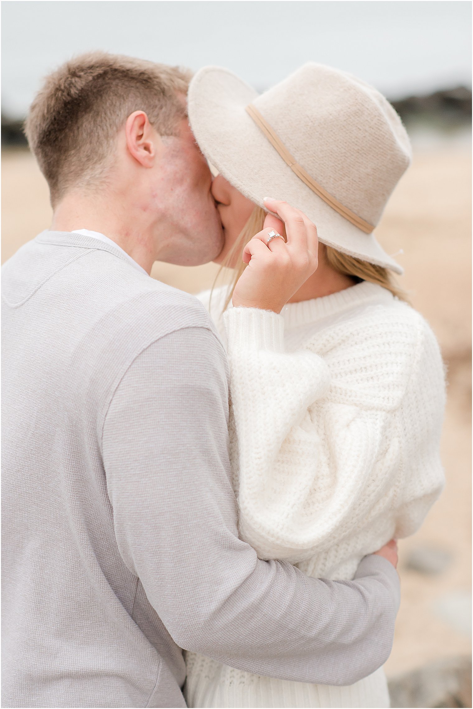 bride holds brim of floppy hat showing off engagement ring