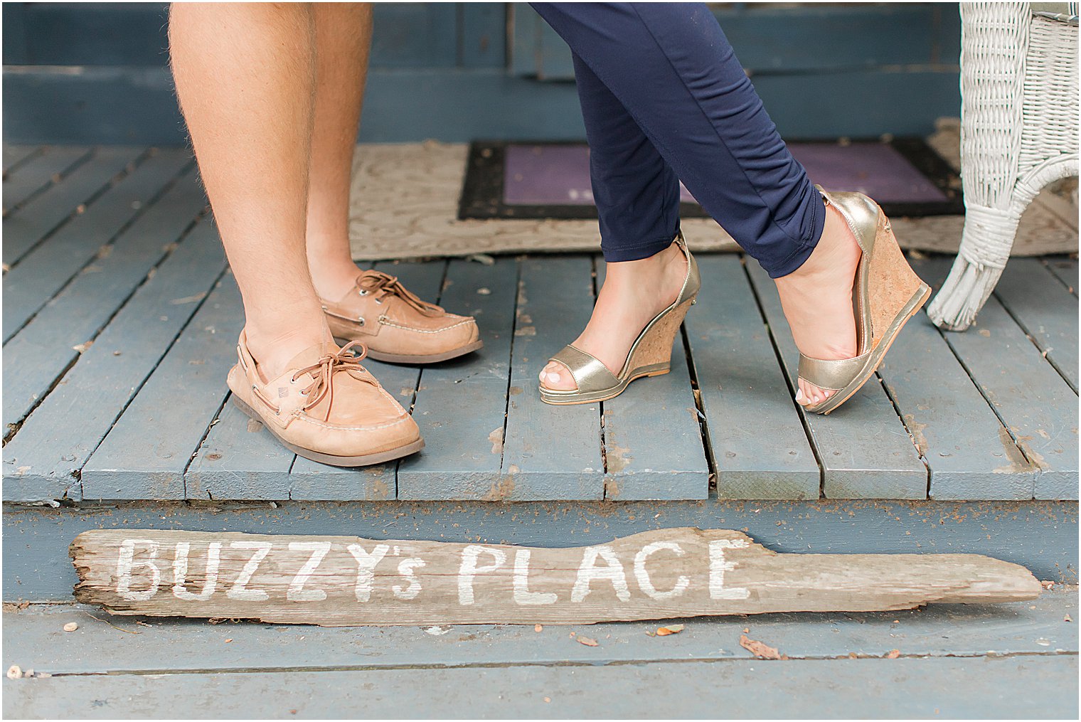 photo of engaged couple's feet resting above wooden sign