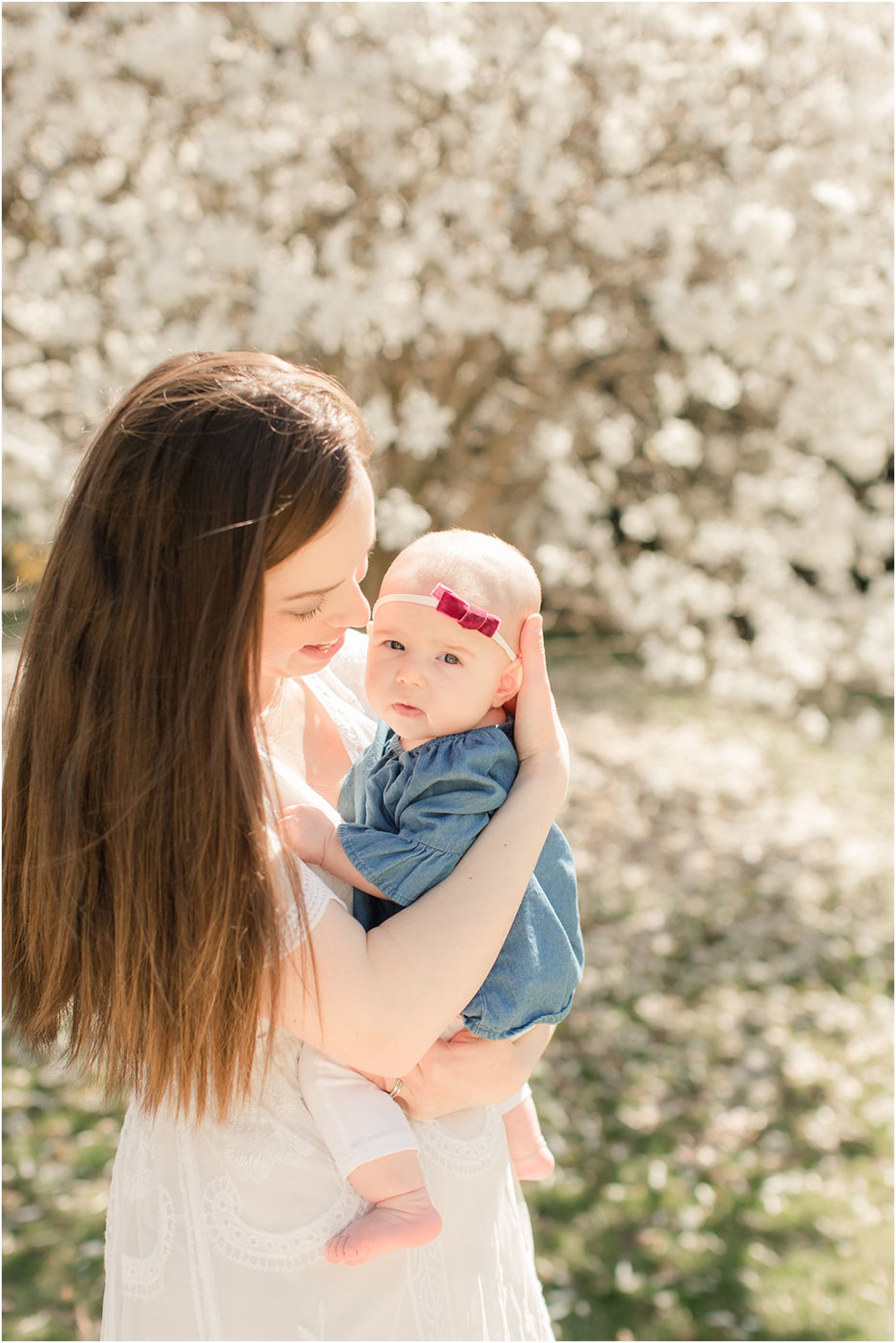 mom holds baby girl by cherry blossom tree in New Jersey