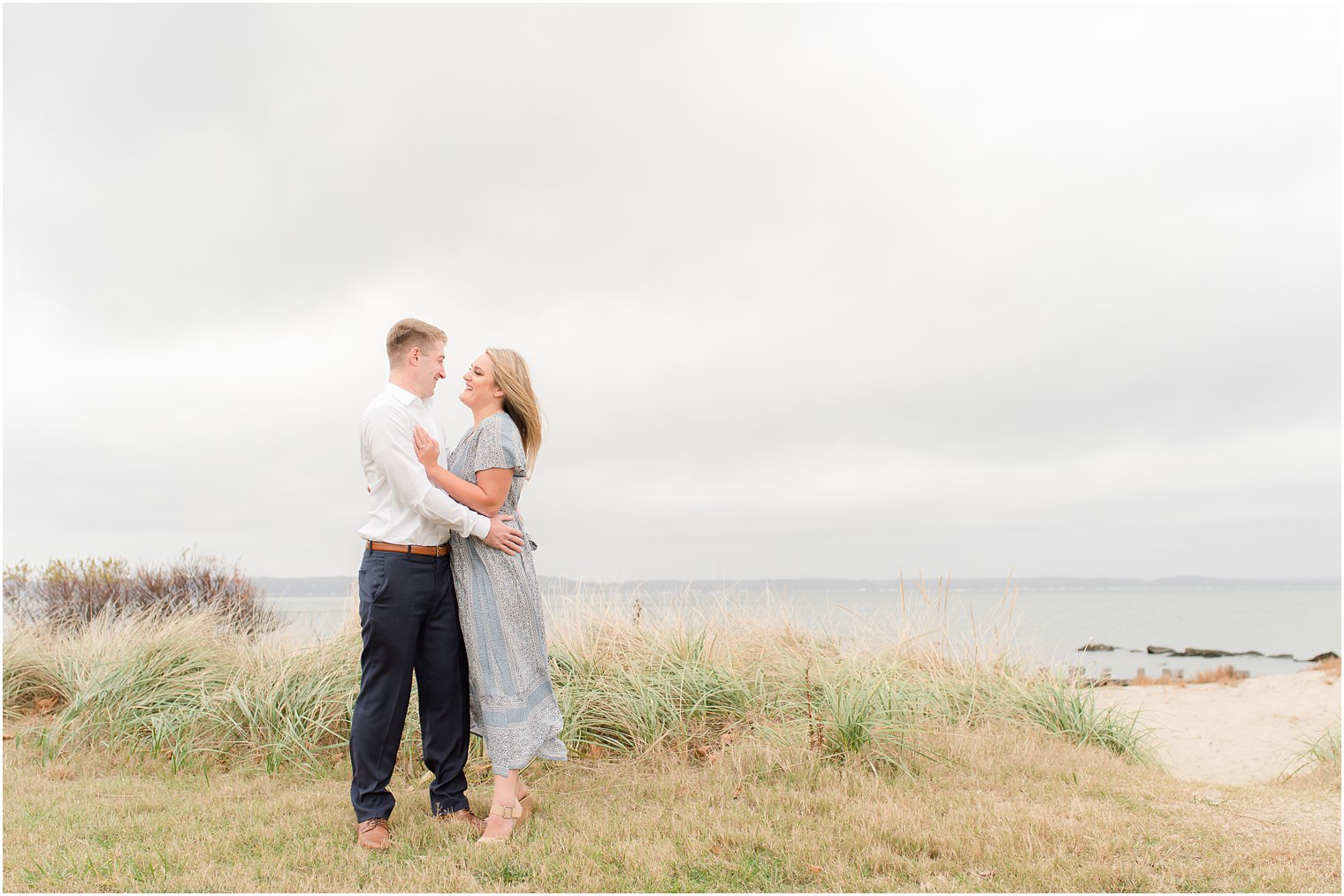 bride and groom laugh by tall grass at Sandy Hook Beach