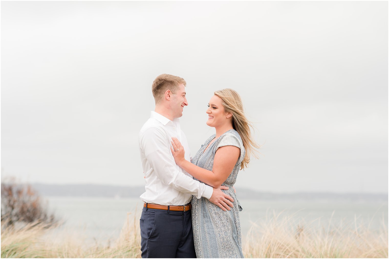 bride and groom pose by tall grass at Sandy Hook Beach