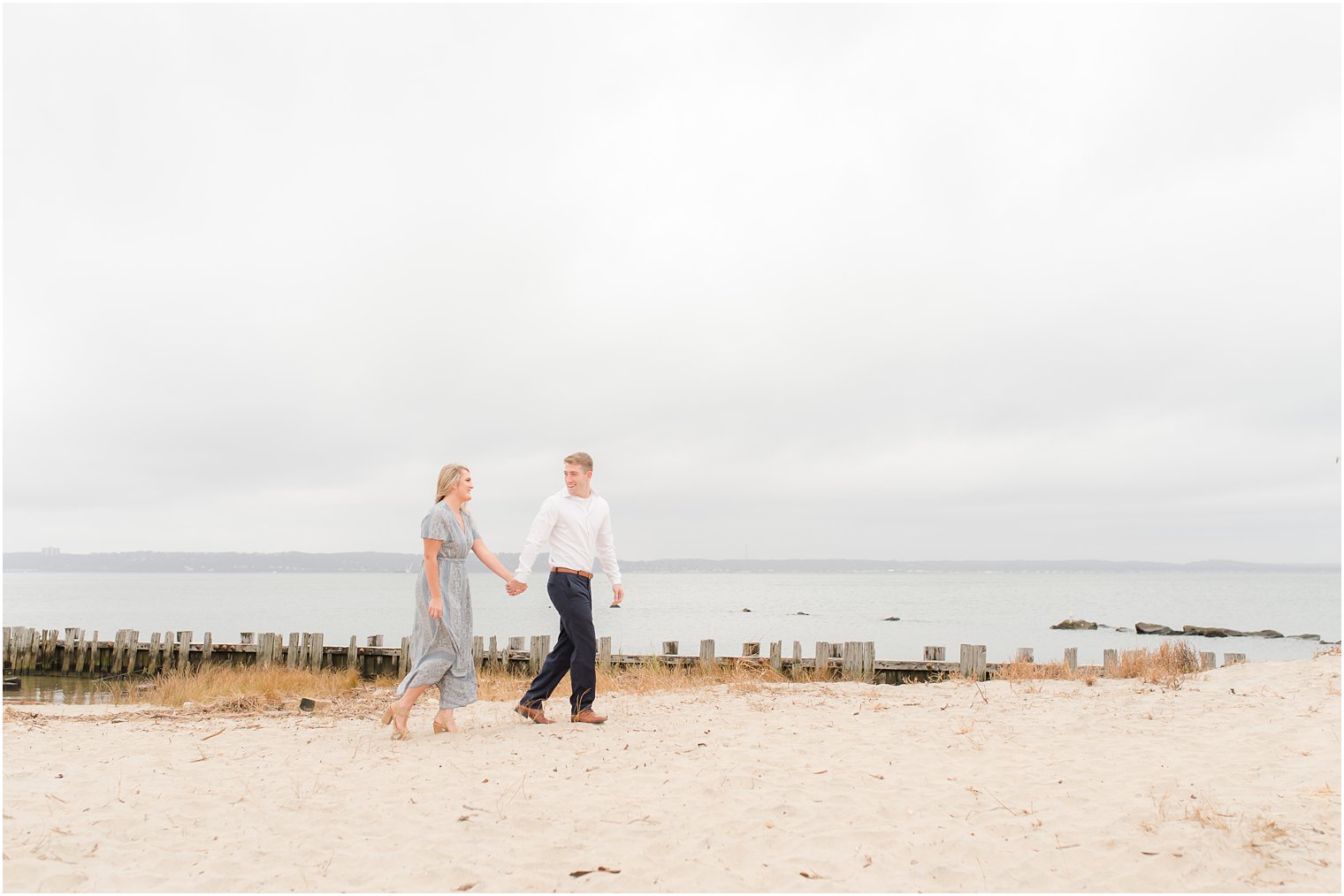 bride and groom hold hands walking along Jersey Shore beach 