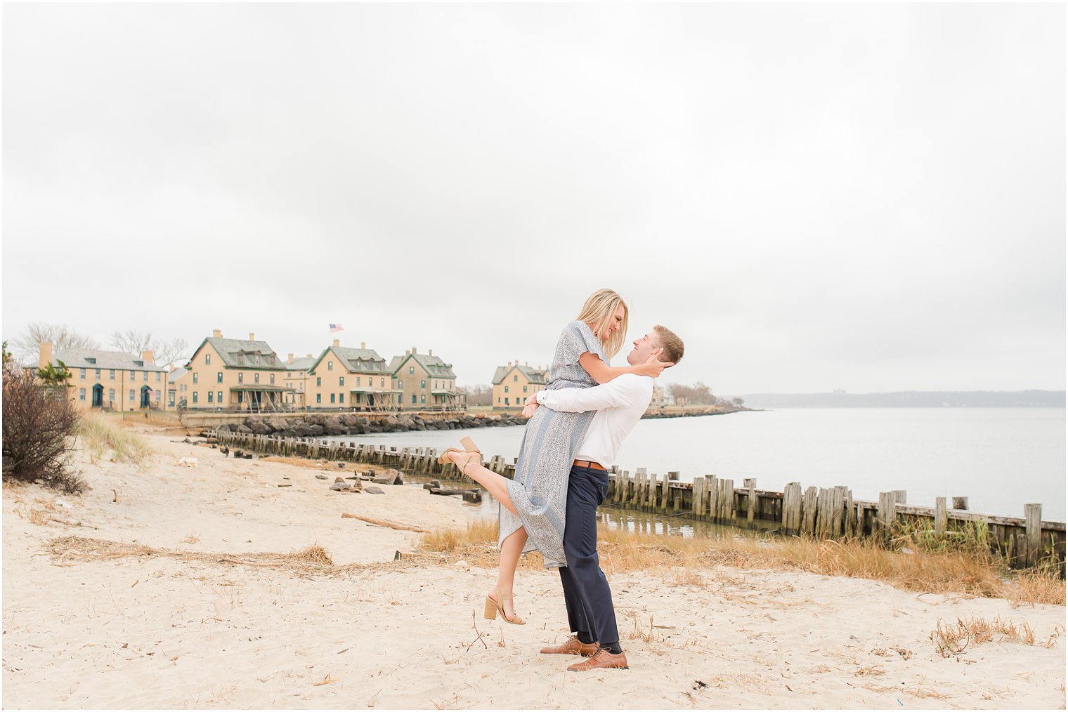 groom lifts bride during Atlantic Highlands NJ engagement session on the beach