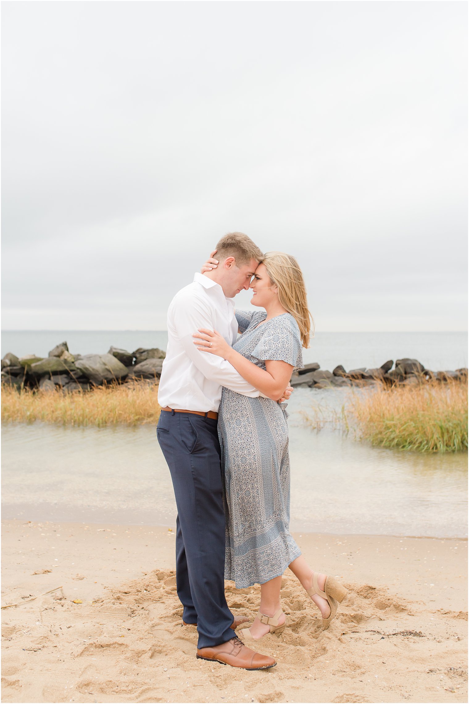 romantic engagement photos at Sandy Hook with couple standing nose to nose by water