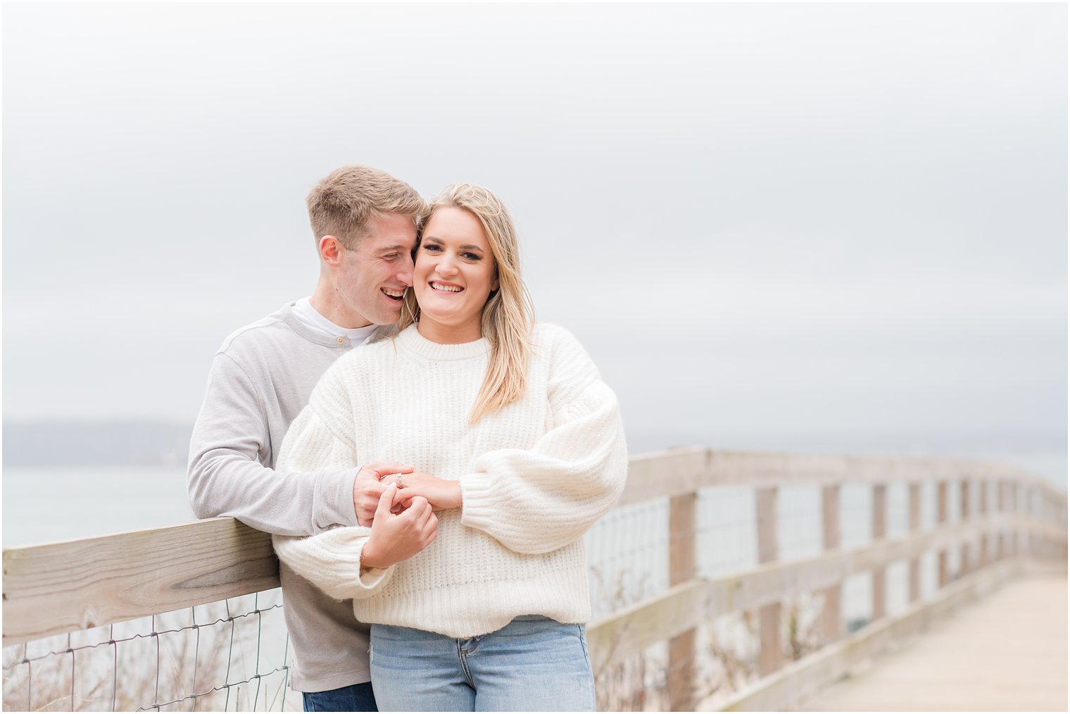 engaged couple laughs during engagement photos at Sandy Hook