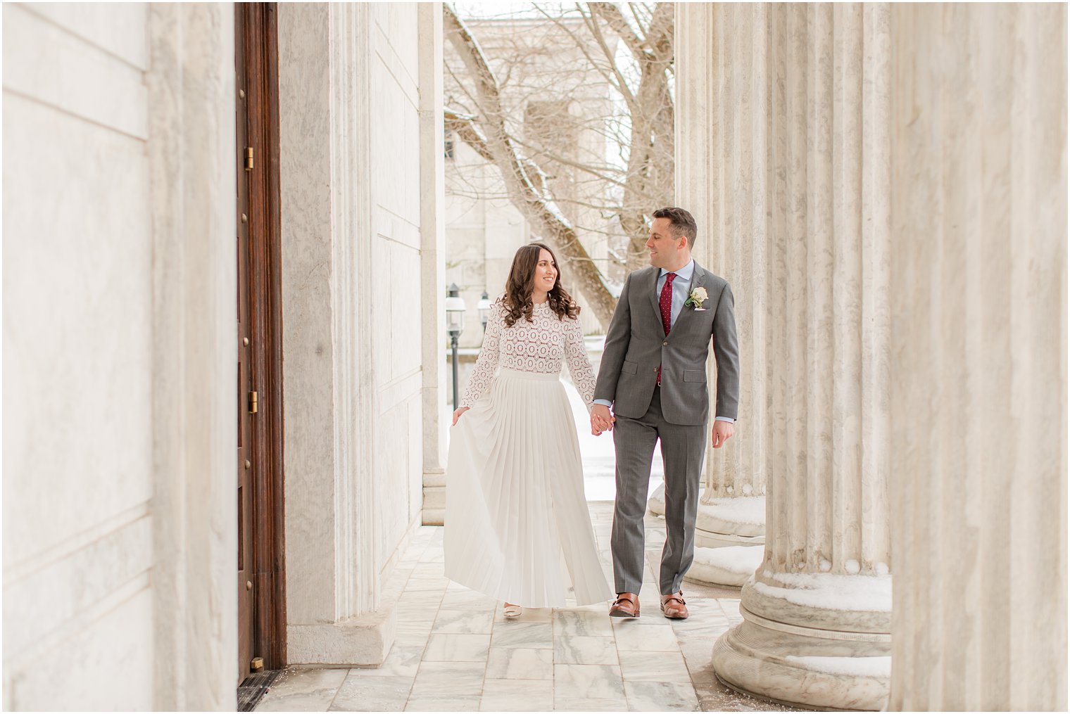 married couple holds hands walking through Princeton University building on snow day