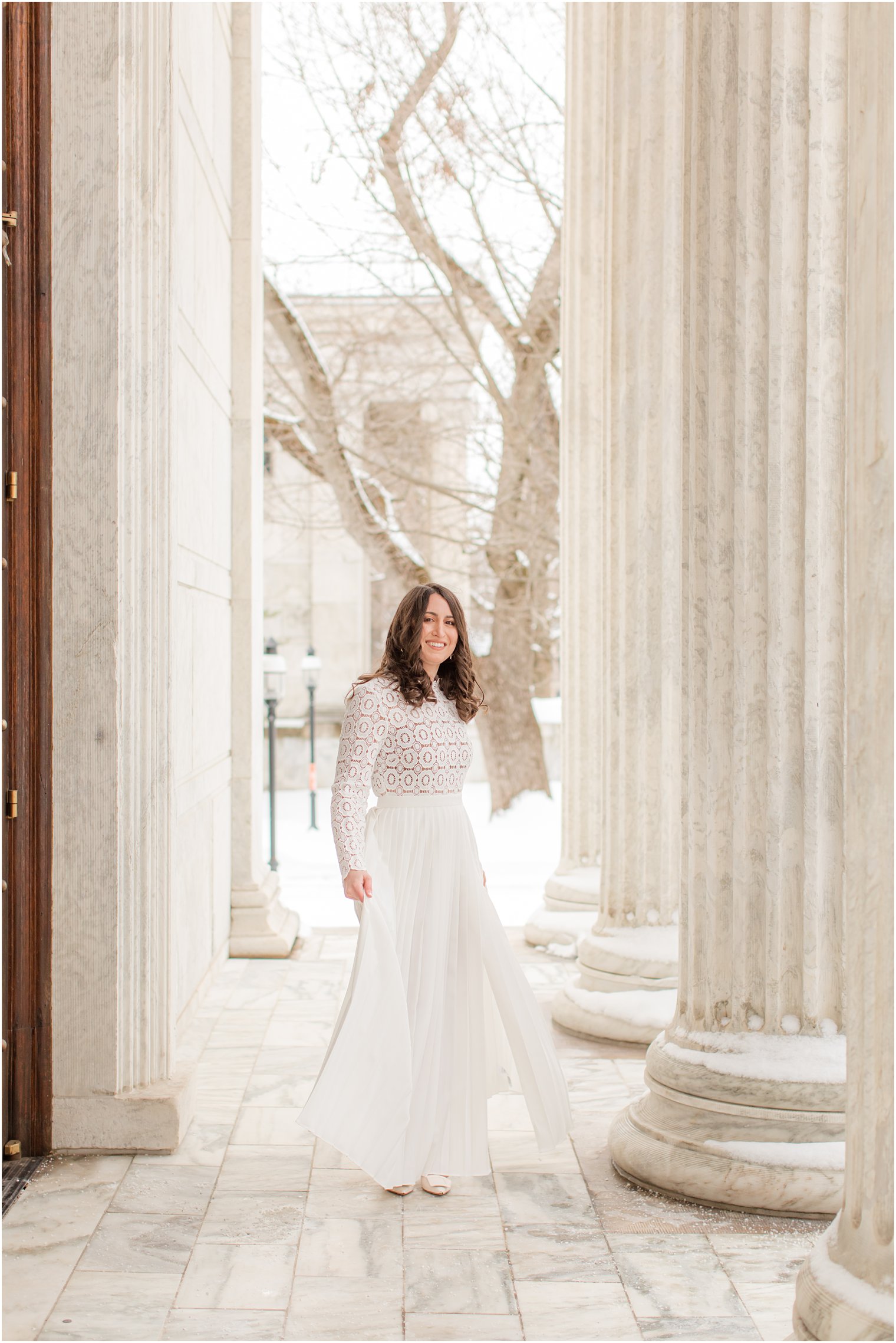 bride in white dress twirls during wedding portraits under pillars at Princeton University 