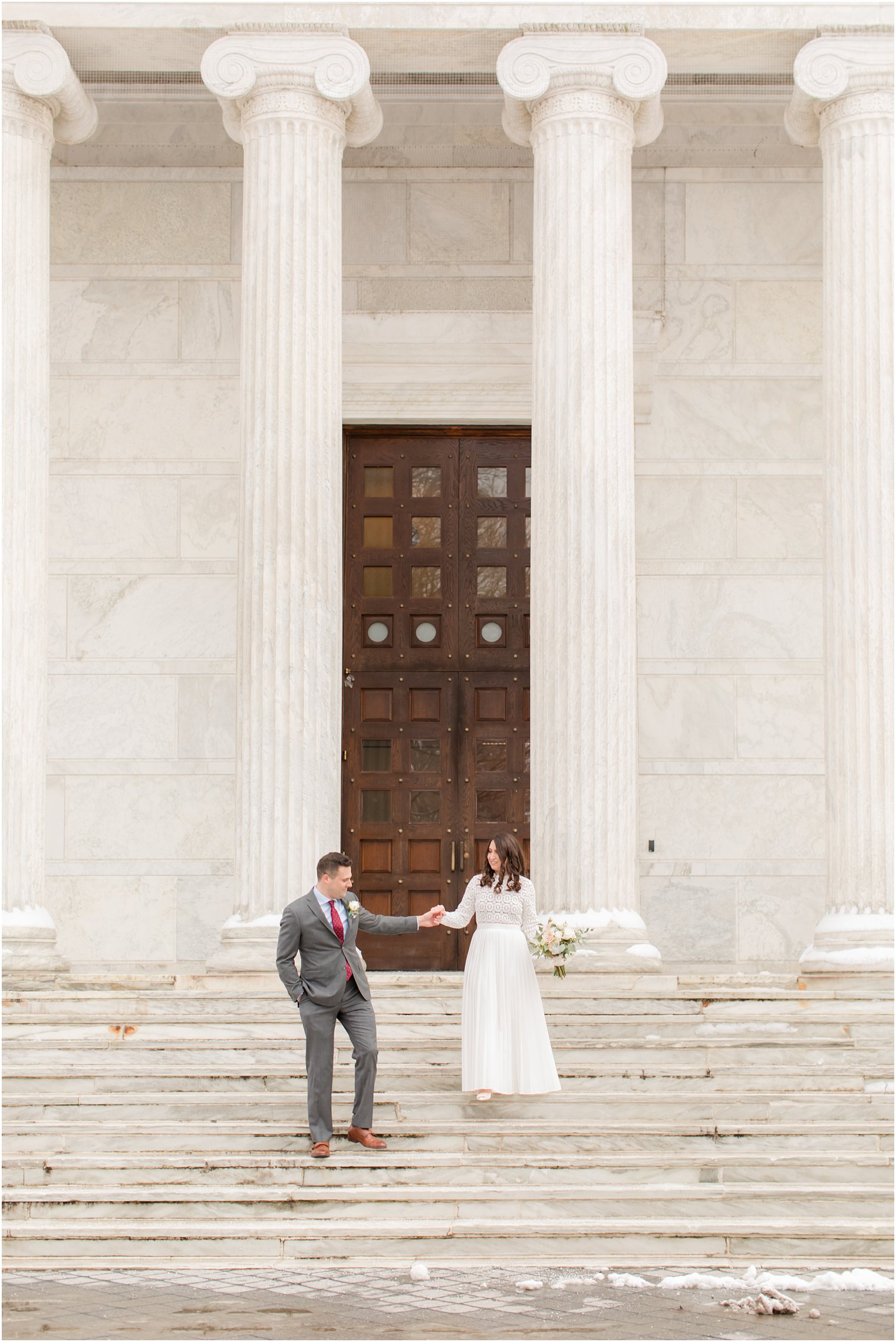 groom helps bride down steps at Princeton University building 