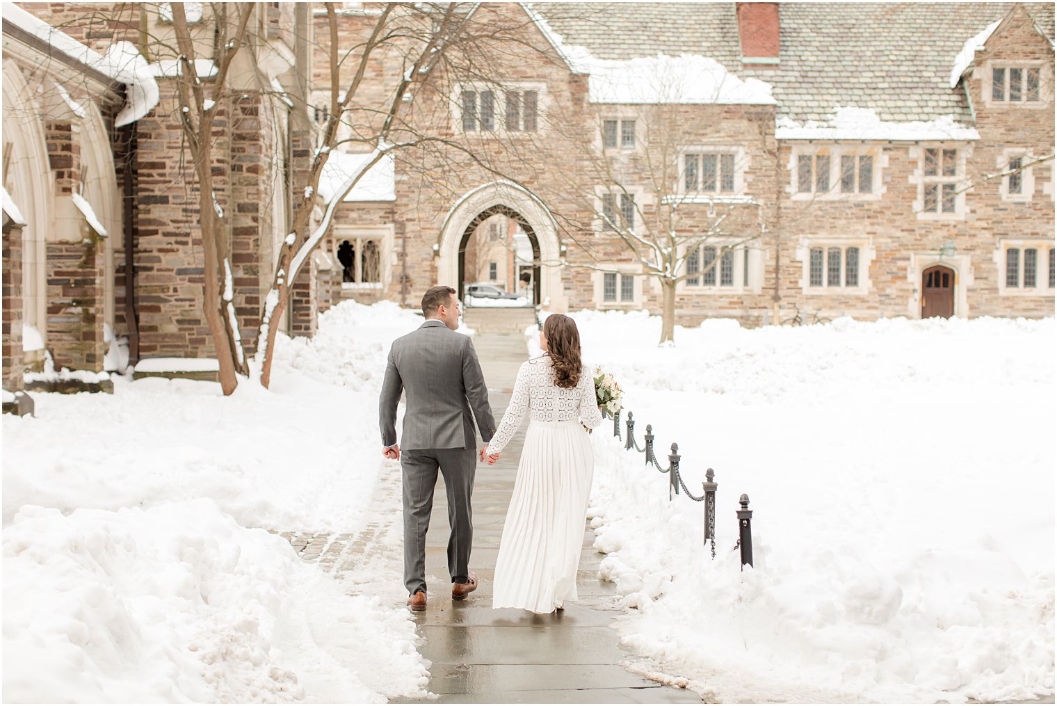 newlyweds hold hands walking around Princeton University on winter wedding day