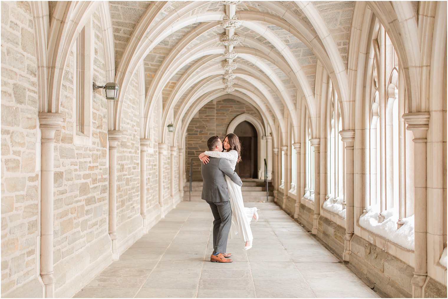 groom lifts bride up in covered walkway at Princeton University 