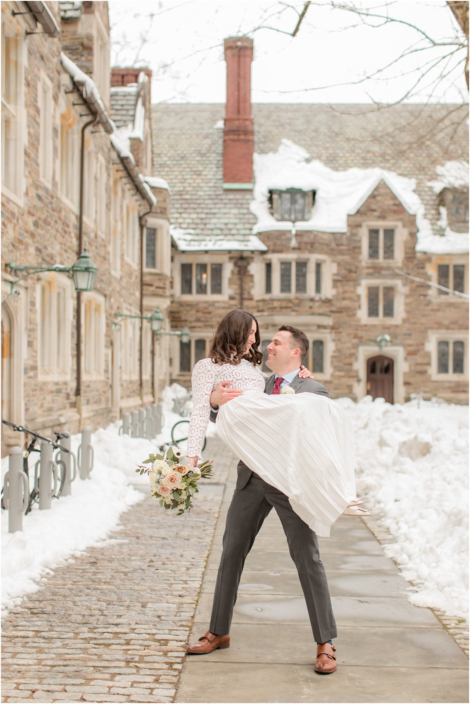 groom lifts bride up on sidewalk at Princeton University 