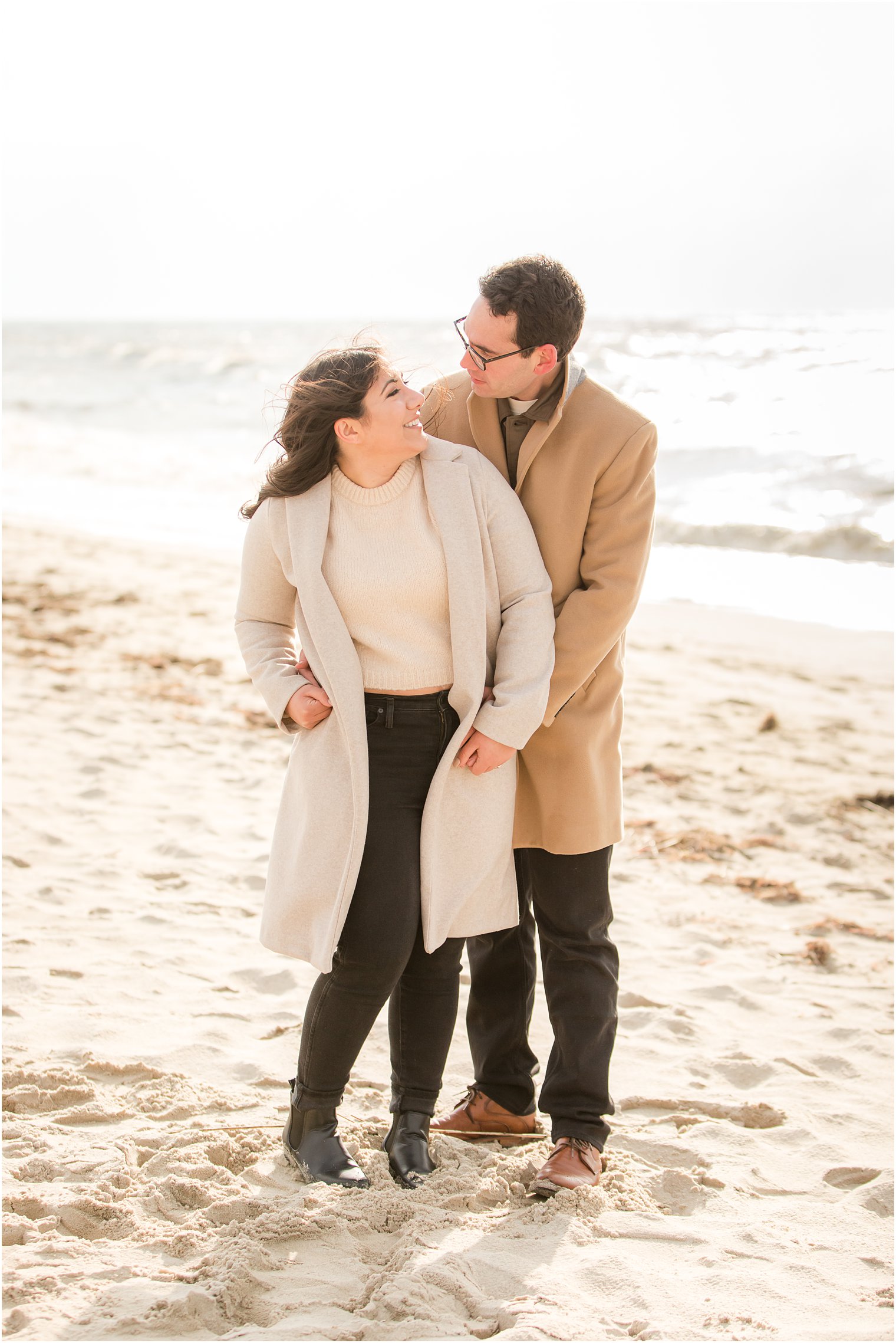 Photo of engaged couple wearing beige sweaters and black pants