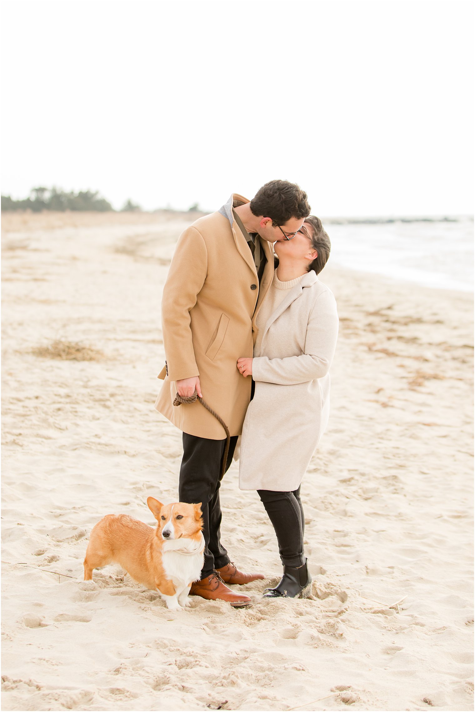 Couple kissing and posing with Corgi