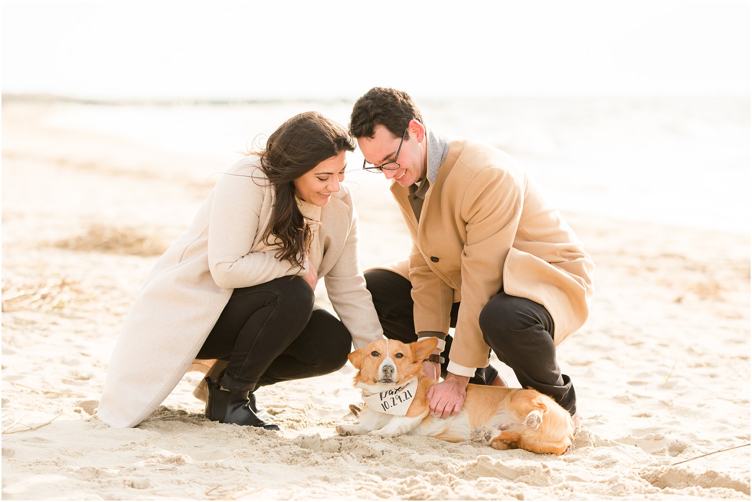 Corgi wearing a Save the Date bandana with engaged couple at the beach