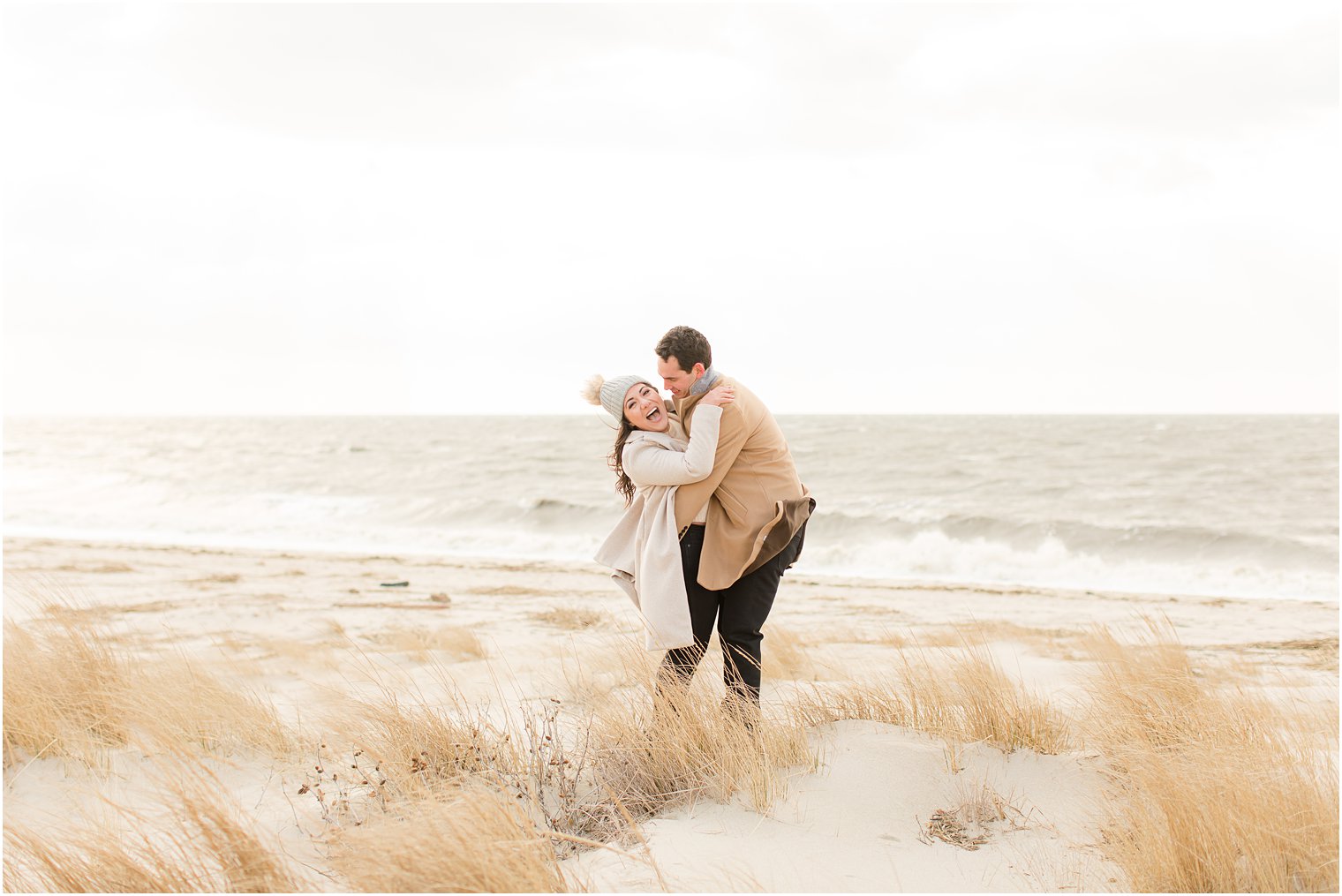 Engaged couple posing for photos on the beach on Sunset Beach in Cape May