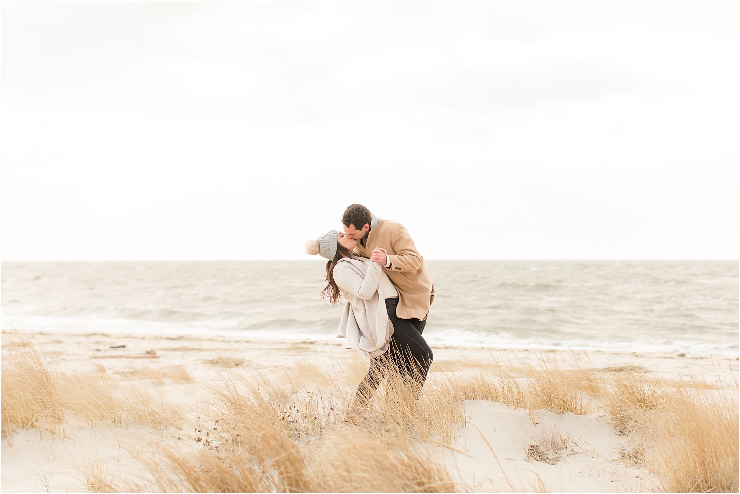 Engaged couple kissing in the sand dunes on the beach in Cape May