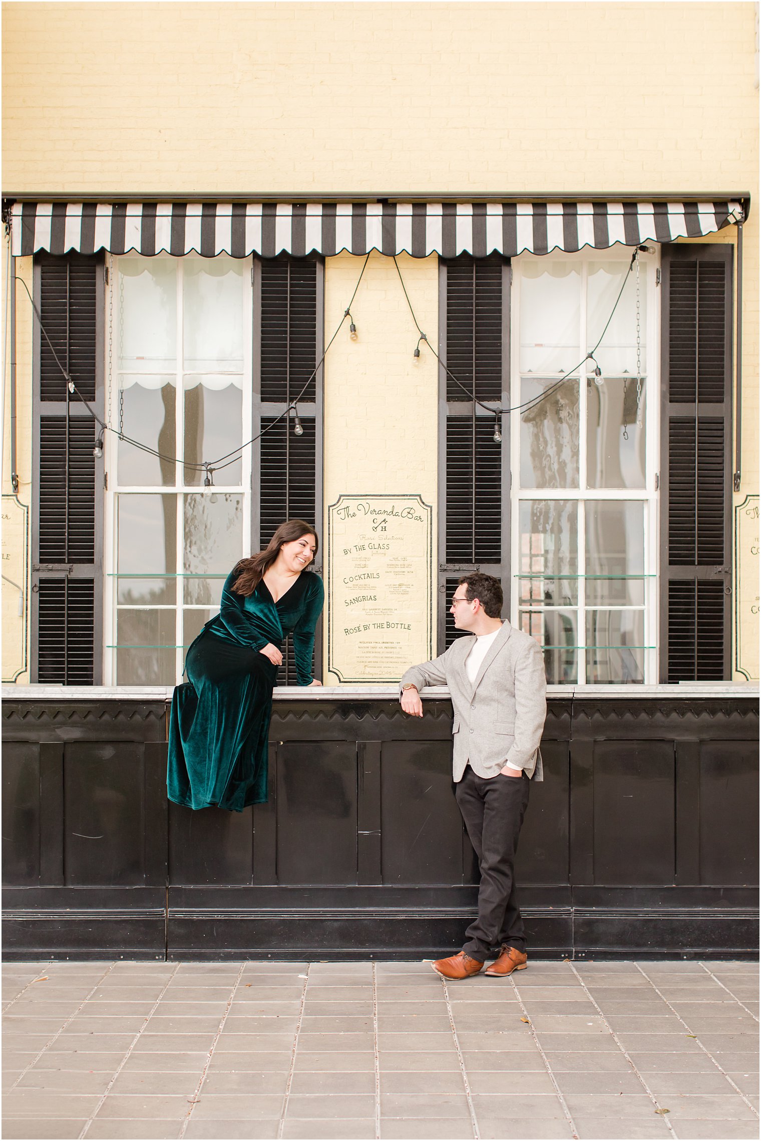 Groom talking to bride sitting on bar in front of Congress Hall in Cape May NJ