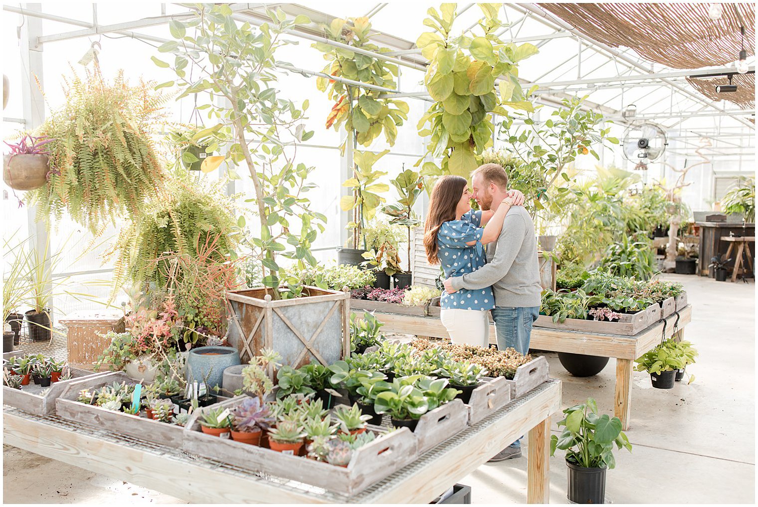New Jersey couple hugs between plant stands at Herbary at Bear Creek