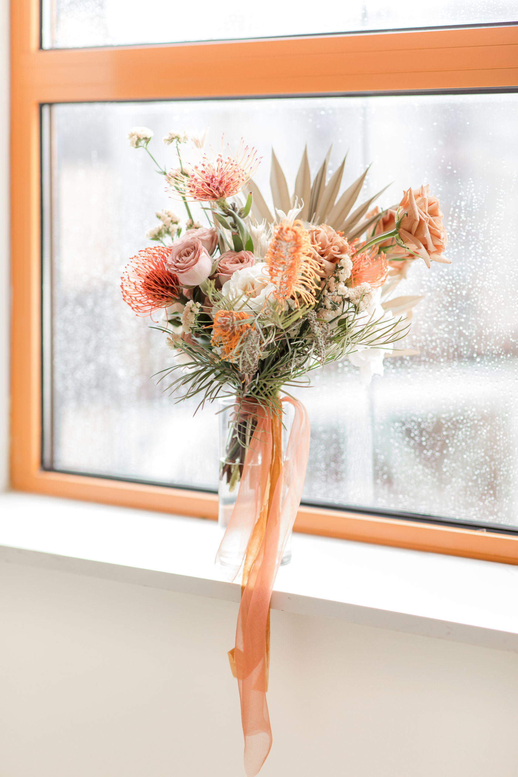 modern wedding bouquet with peach and white sits in window sill at Ironworks at Pencoyd Landing