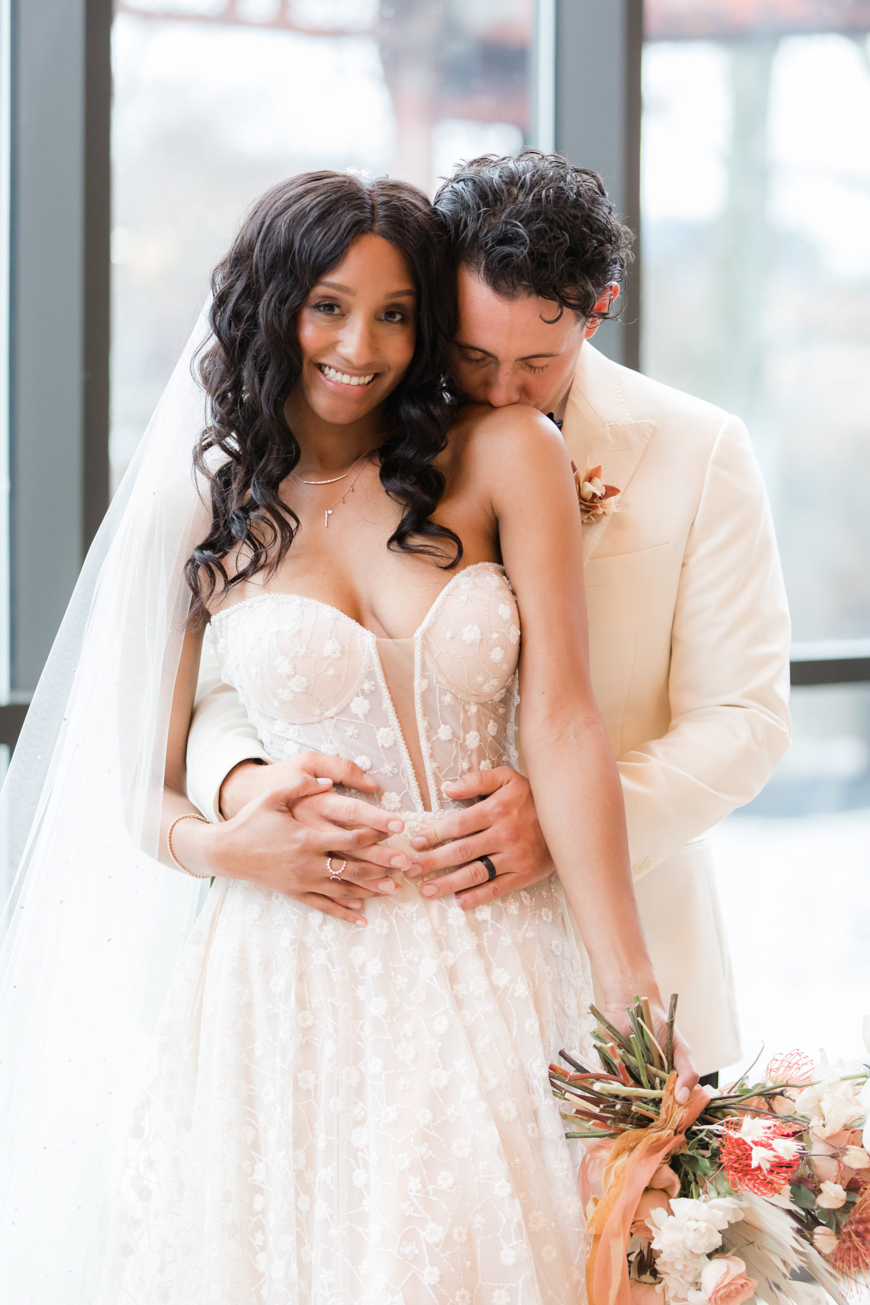 groom kisses bride's shoulder while hugging her during Philadelphia wedding day