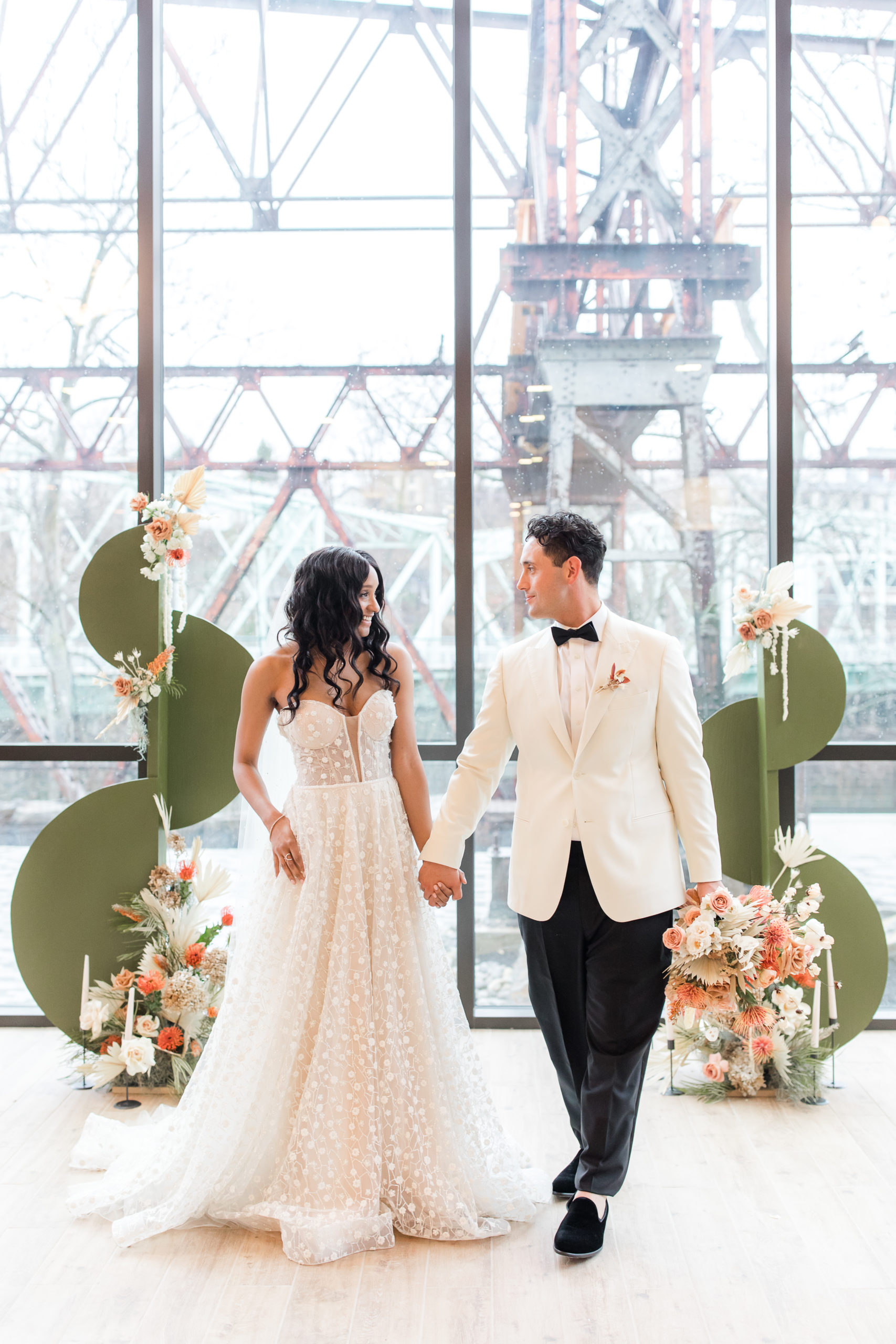 bride and groom hold hands walking in front of geometric ceremony decor in Philadelphia PA