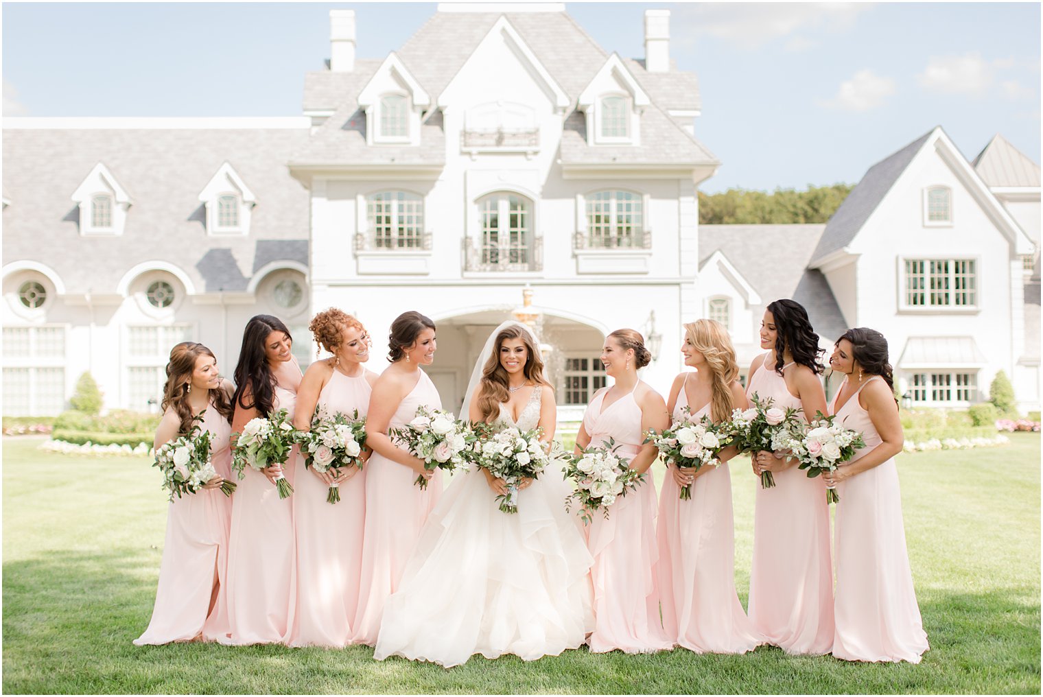 bride and bridesmaids in blush pink pose outside NJ wedding venue