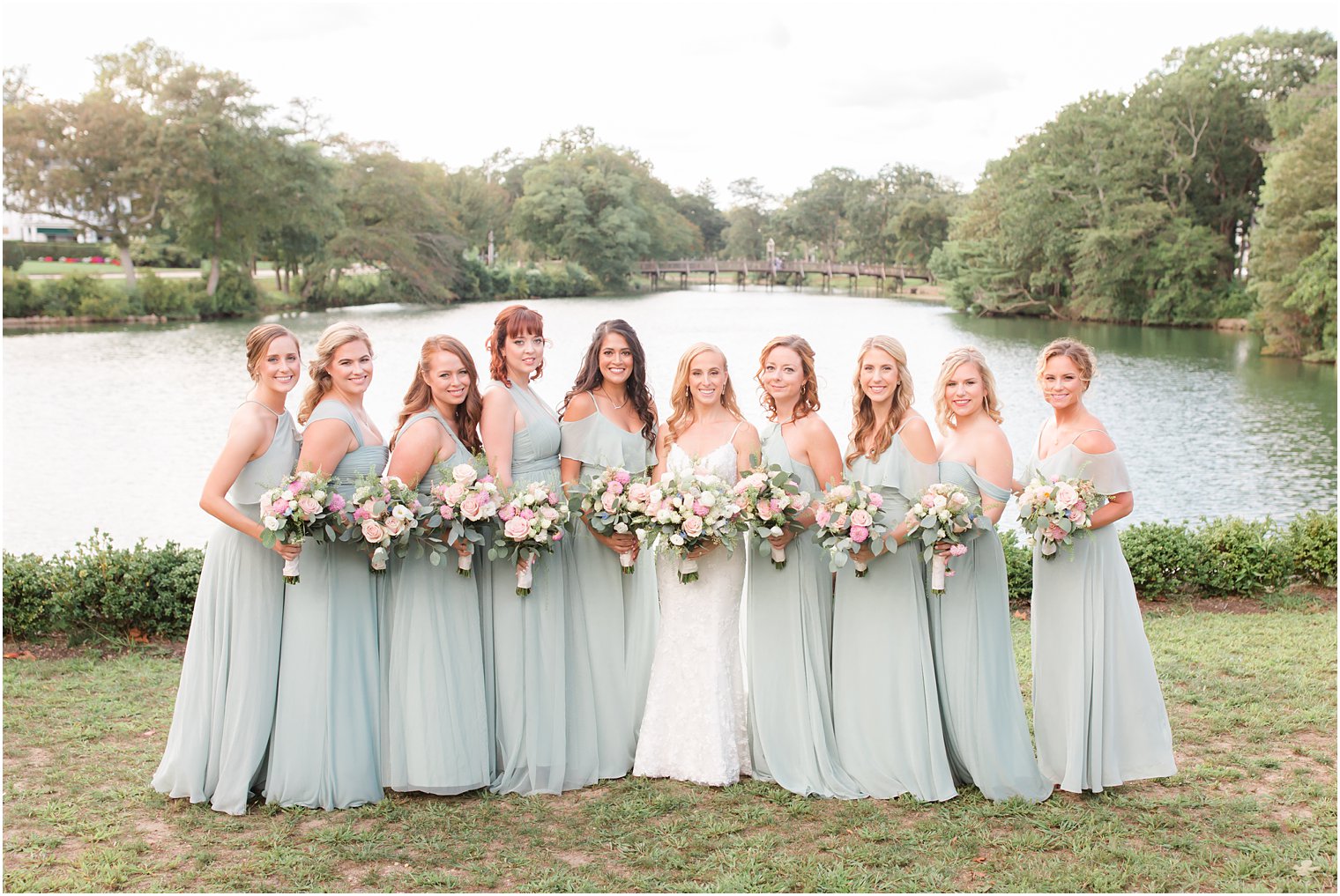 bride poses with bridesmaids in sage green gowns