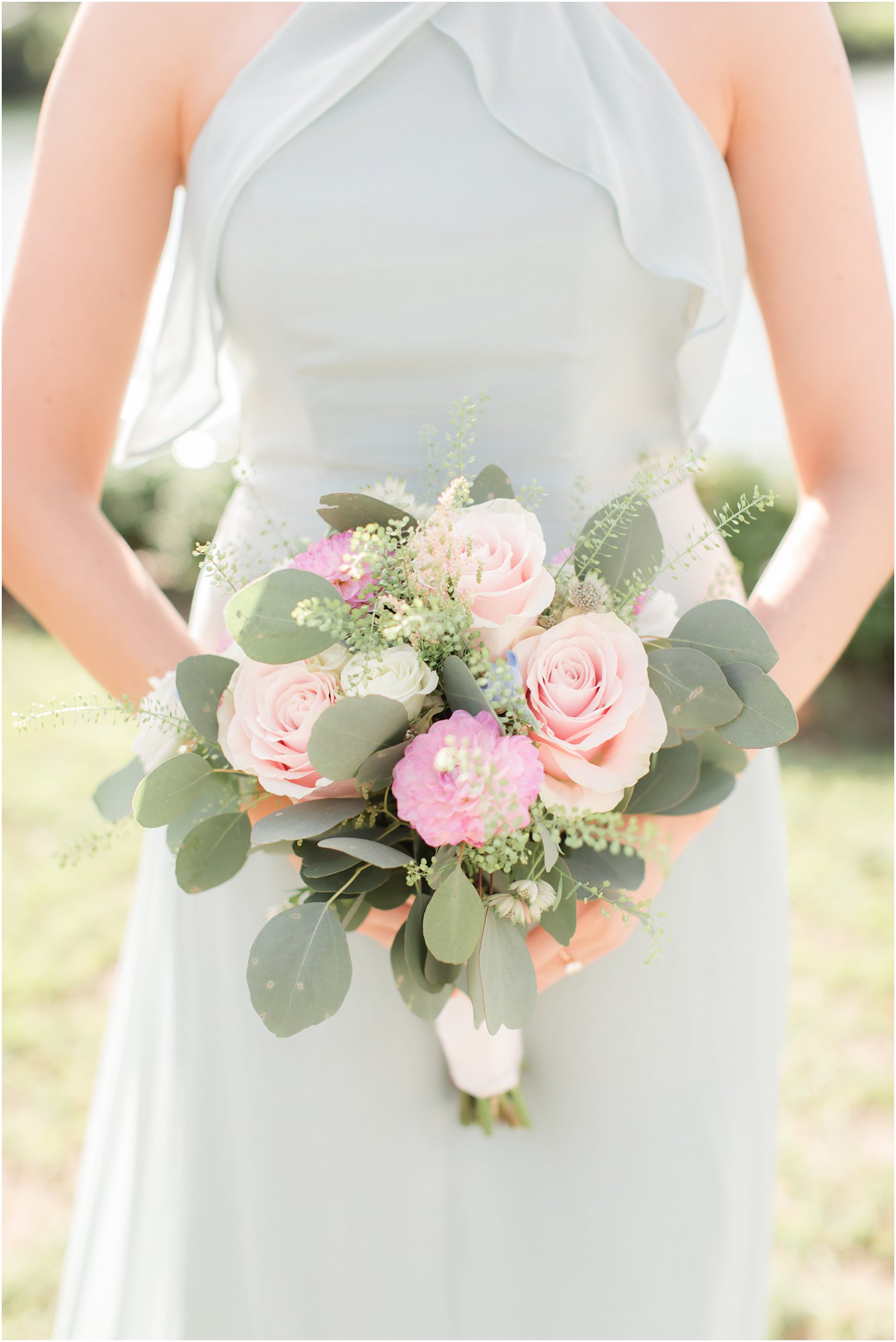 bridesmaid in sage green gown holds bouquet with pops of pink